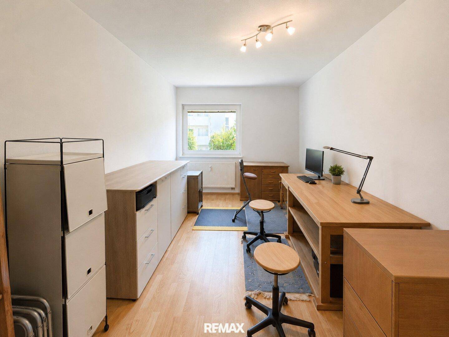 Funktionales Arbeitszimmer mit zwei Schreibtischen, Holzfußboden und ausreichend Stauraum für Büromaterialien.