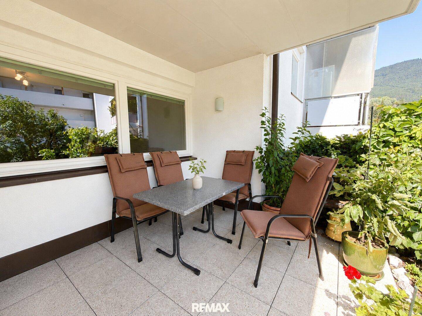 Überdachter Balkon mit Sitzgelegenheiten und Pflanzen, bietet einen schönen Blick auf die umliegende Landschaft.