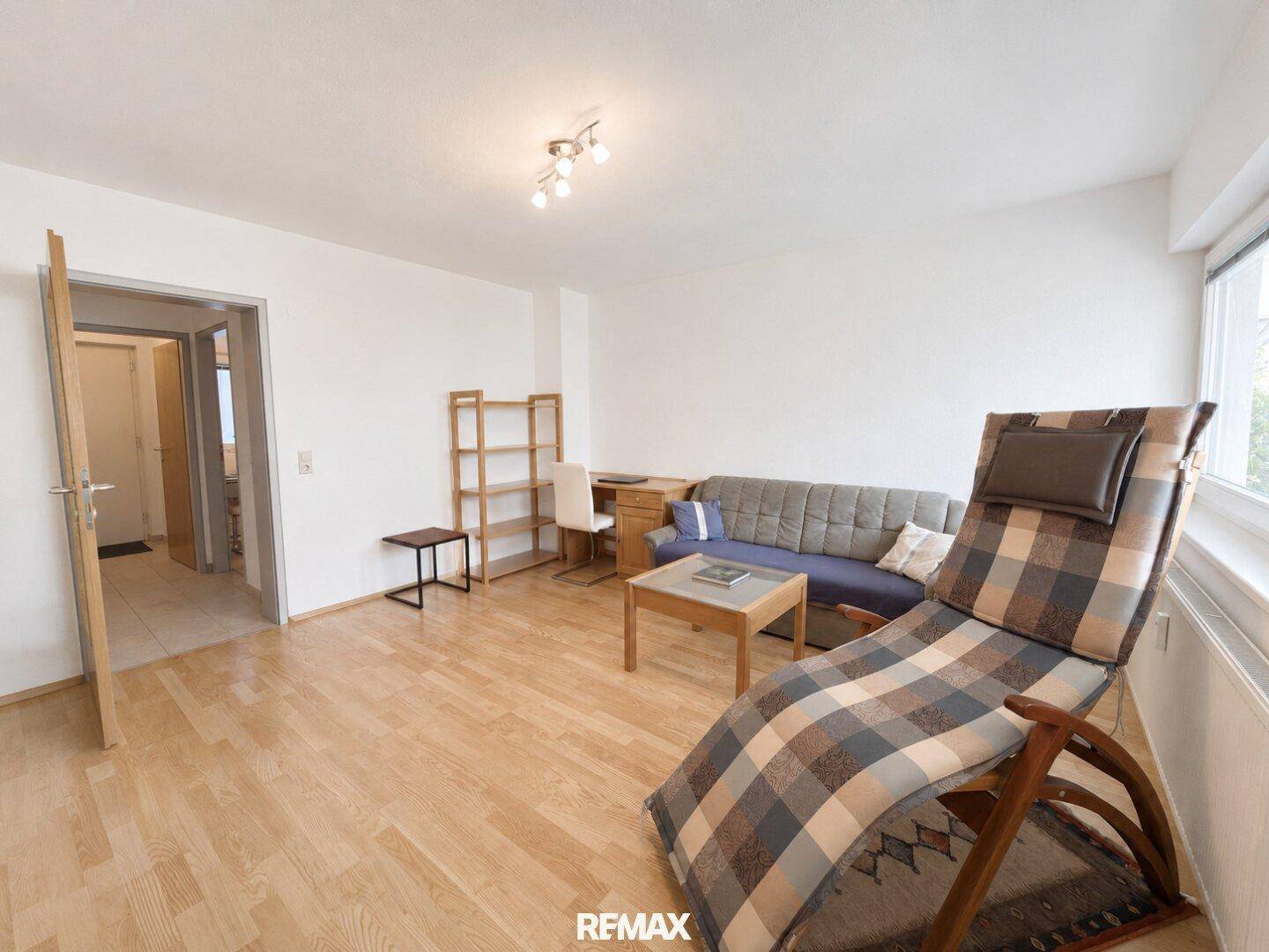 Geräumiges Wohnzimmer mit Holzfußboden und Zugang zu einem Flur, ideal für entspannte Stunden.