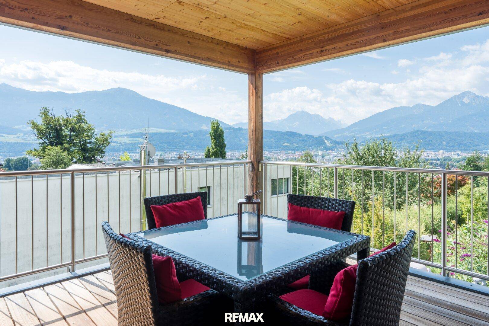 Geräumiger Balkon mit Holzboden und Sitzgelegenheiten, bietet einen atemberaubenden Panoramablick auf die Berge.