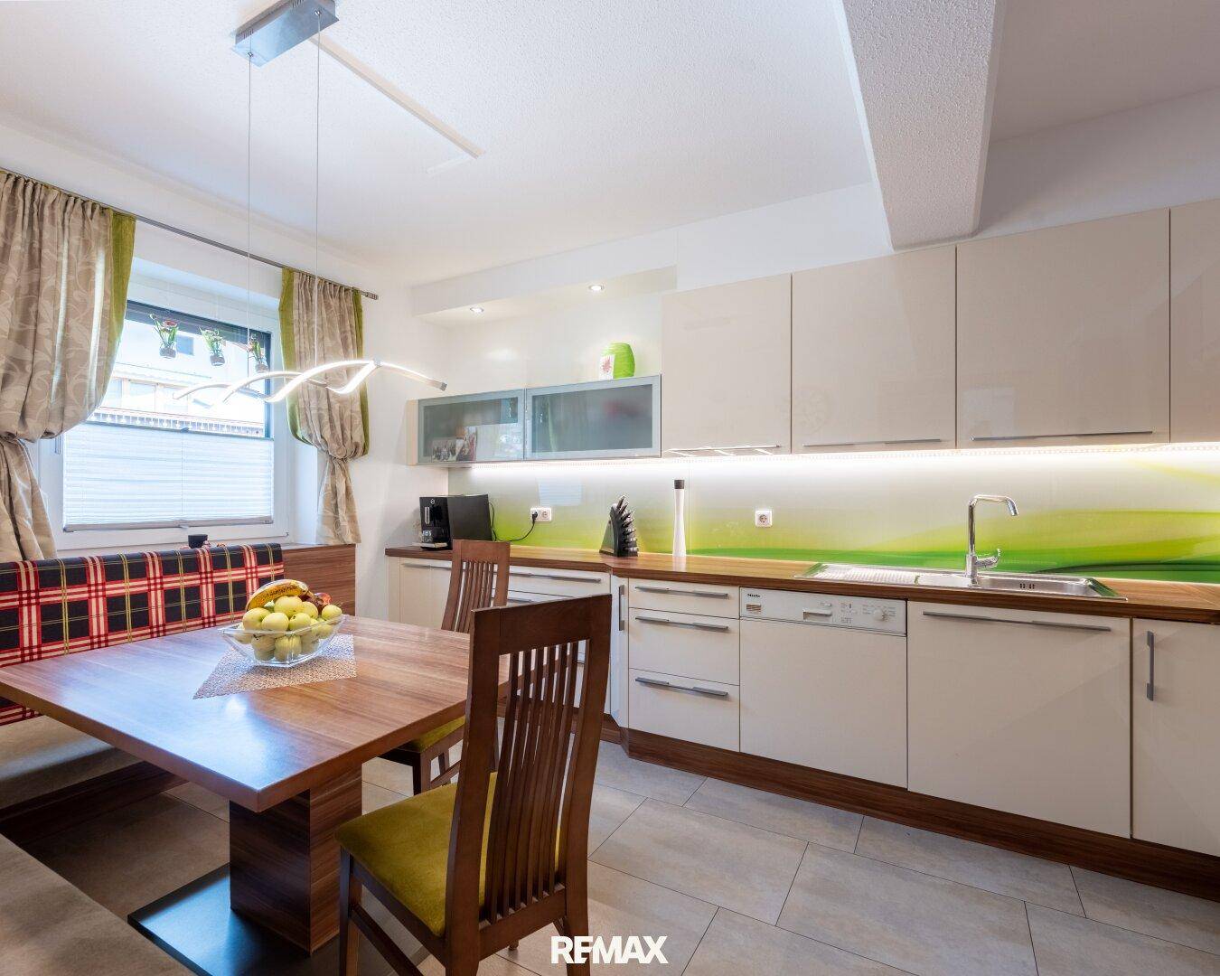 Moderne Einbauküche mit hellem Design, Essbereich und Blick ins Grüne.