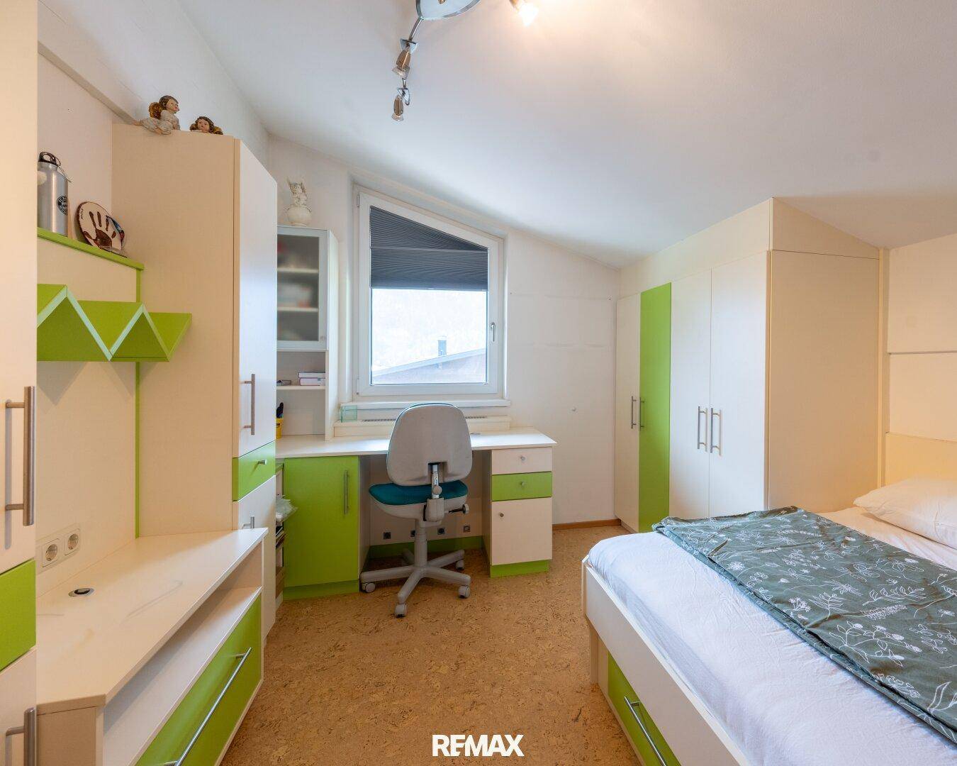 Kinderzimmer mit farbenfrohen Möbeln, Schreibtisch und Dachschräge.
