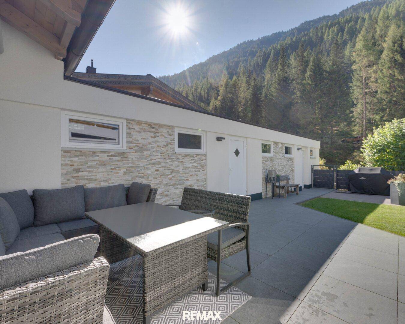 Moderne Terrasse mit bequemen Outdoor-Möbeln und Grillbereich, ideal für entspannte Stunden im Freien.