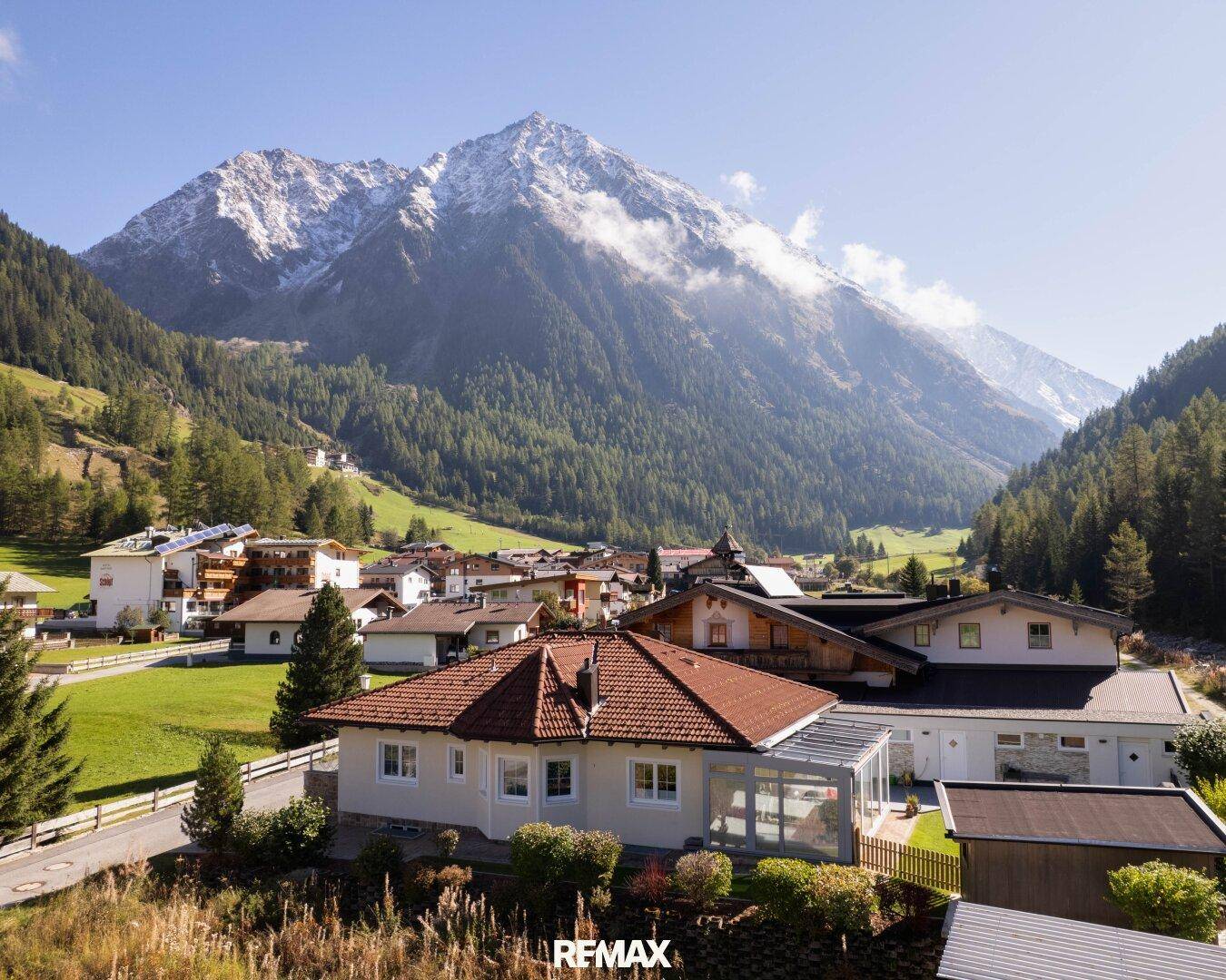 Panoramablick auf das Haus und das umliegende Dorf, eingebettet in eine beeindruckende alpine Berglandschaft.