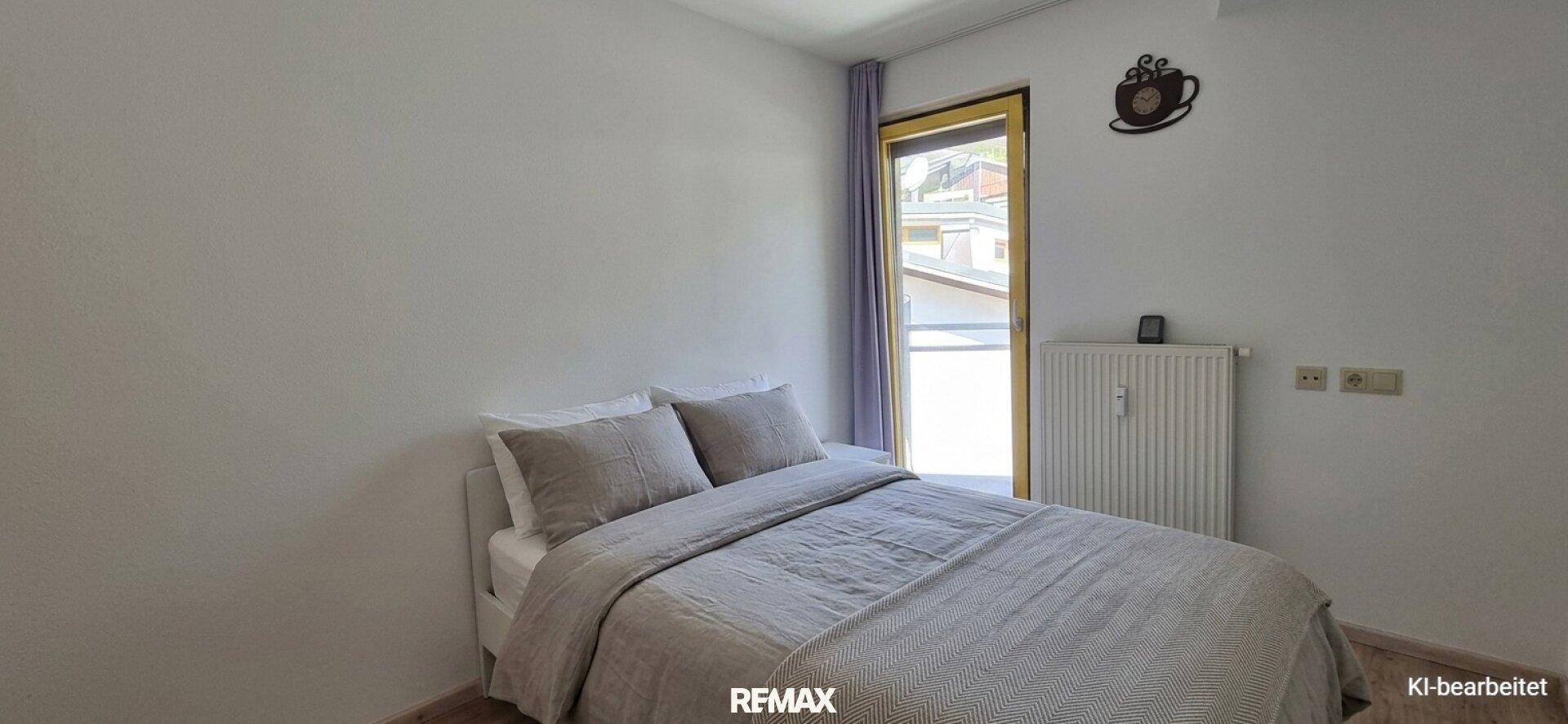 Helles Schlafzimmer mit Doppelbett, Fenster und Heizkörper.