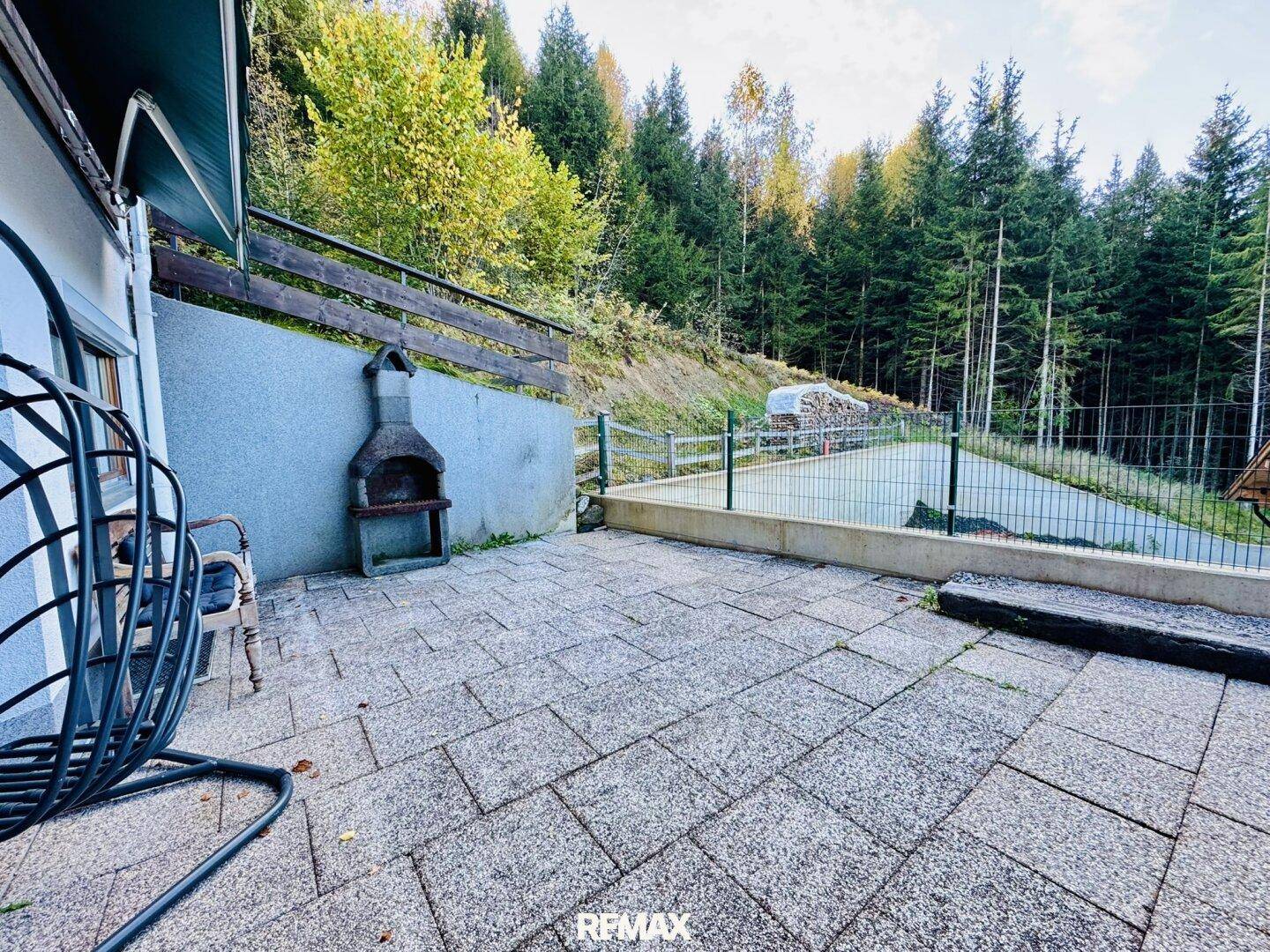 Geräumige gepflasterte Terrasse mit Grillplatz und weitem Blick auf den umliegenden Wald.