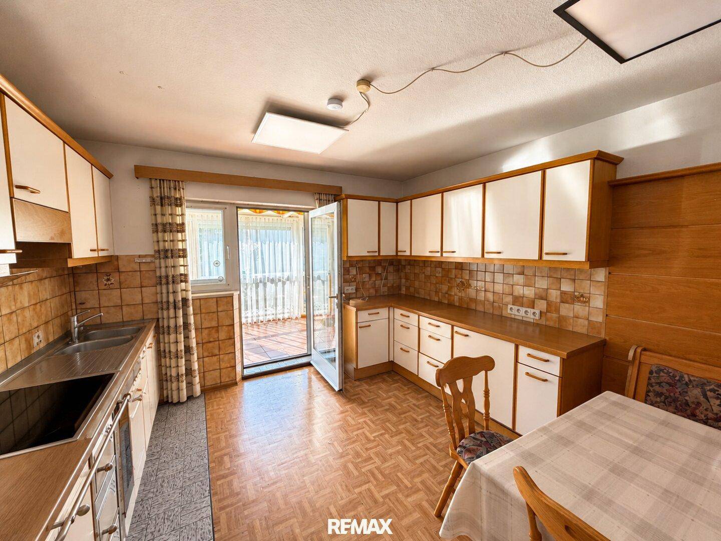 Traditionelle Küche mit Holzschränken, karierten Fliesen und Zugang zu einem Balkon.