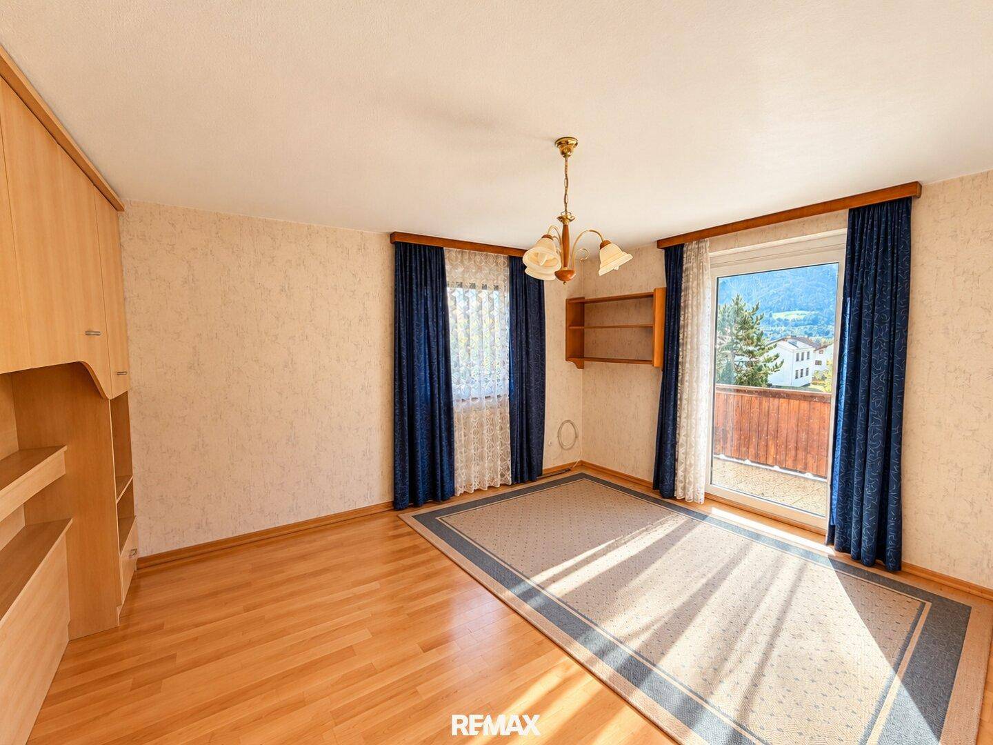 Helles Schlafzimmer mit Holzboden, Einbauschrank und Zugang zu einem Balkon.