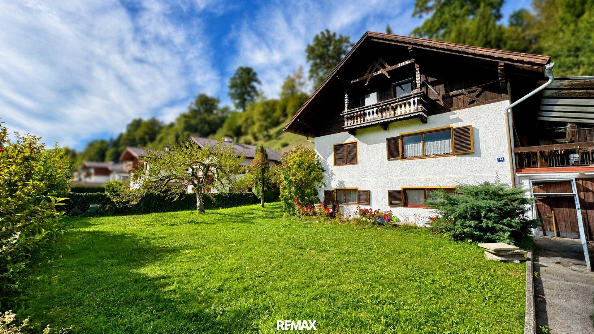 Traditionelles Haus mit gepflegtem Vorgarten und Holzbalkon in sonniger Lage.