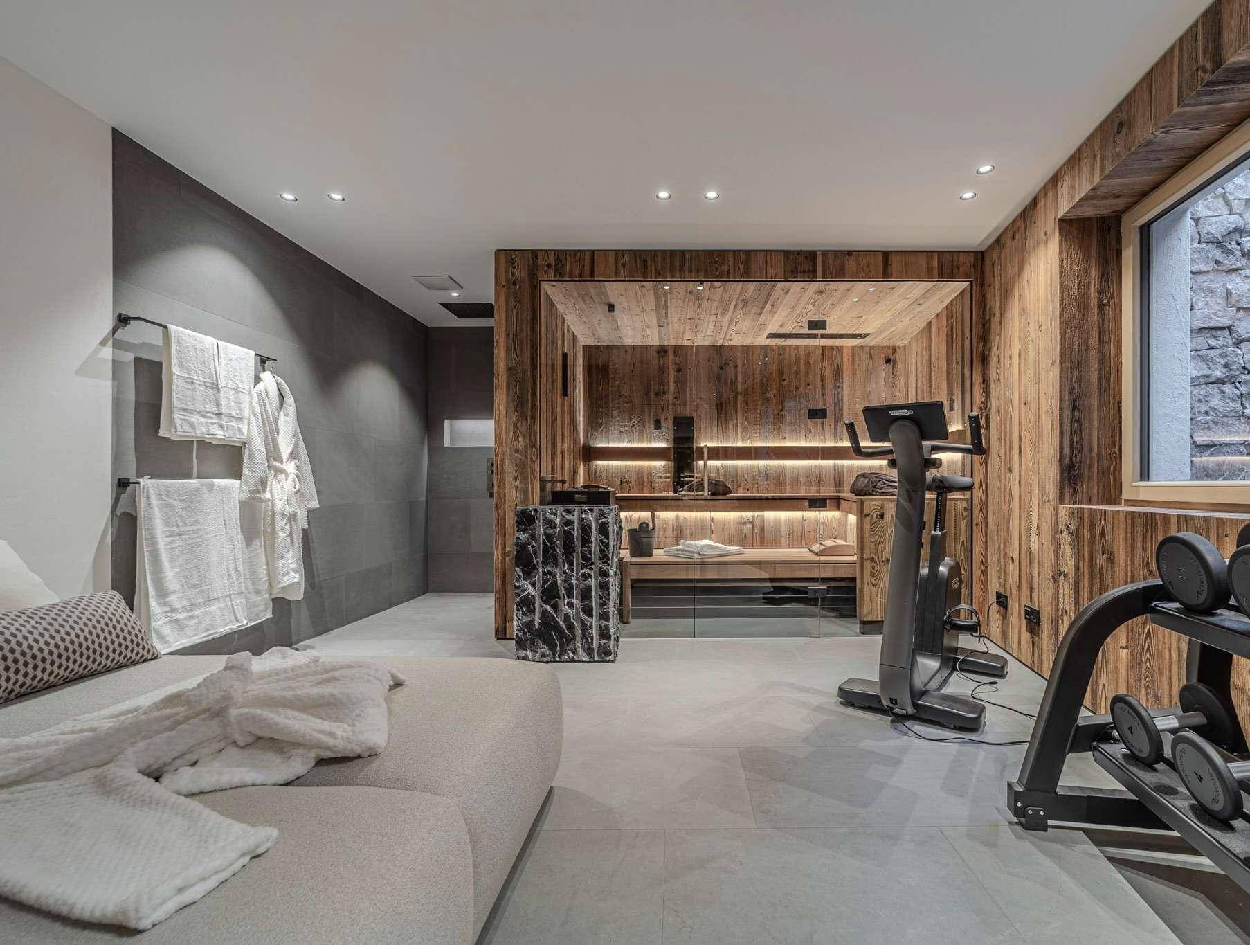 Wellnessbereich mit Sauna, Fitnessgeräten und Entspannungsliege.