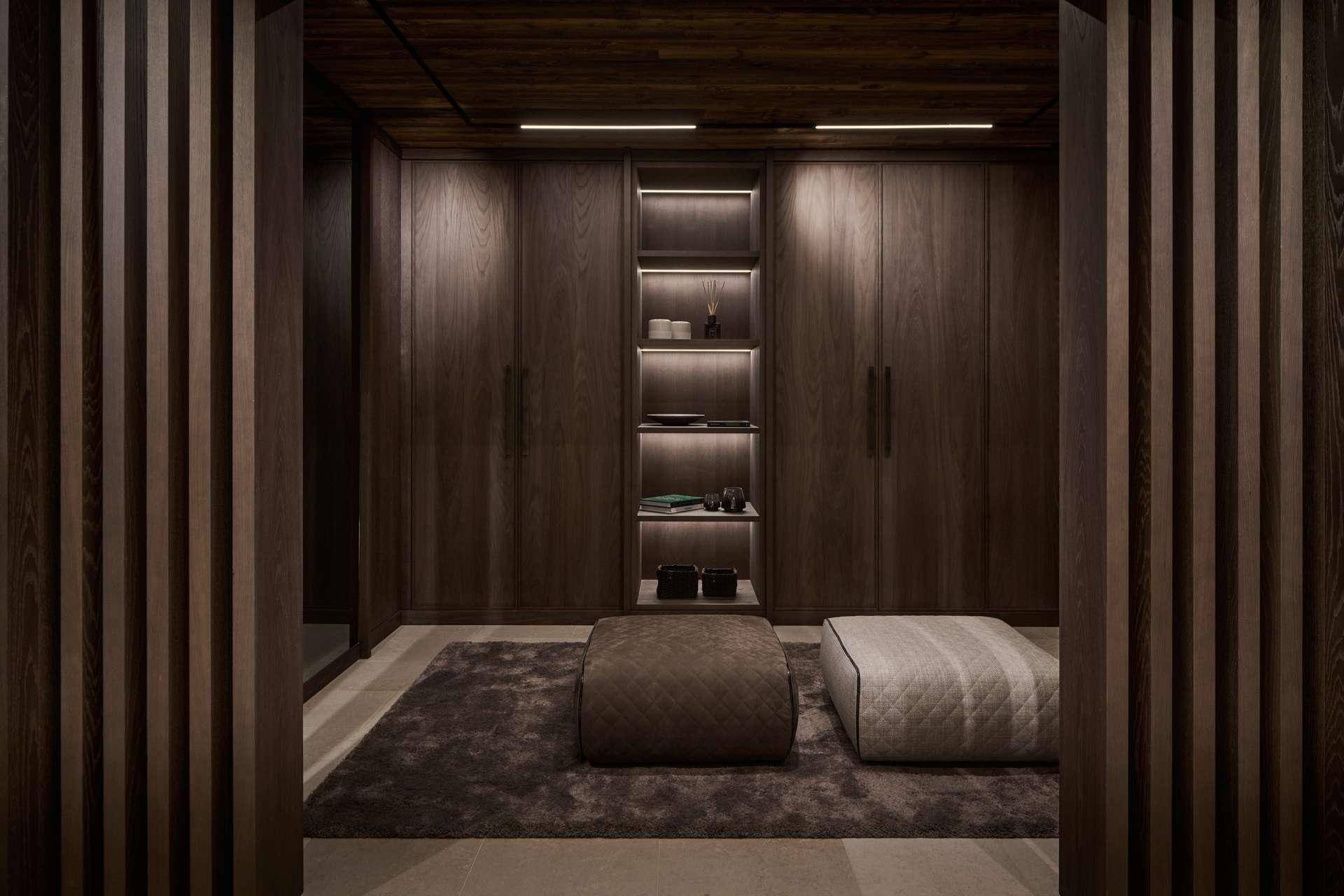 Geräumiger begehbarer Kleiderschrank mit eleganten Holzschränken und Sitzgelegenheiten.