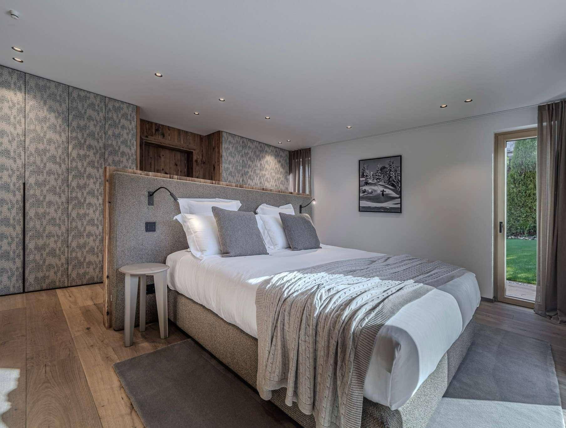 Gemütliches Schlafzimmer mit Holzboden, großem Bett und Zugang zum Garten.
