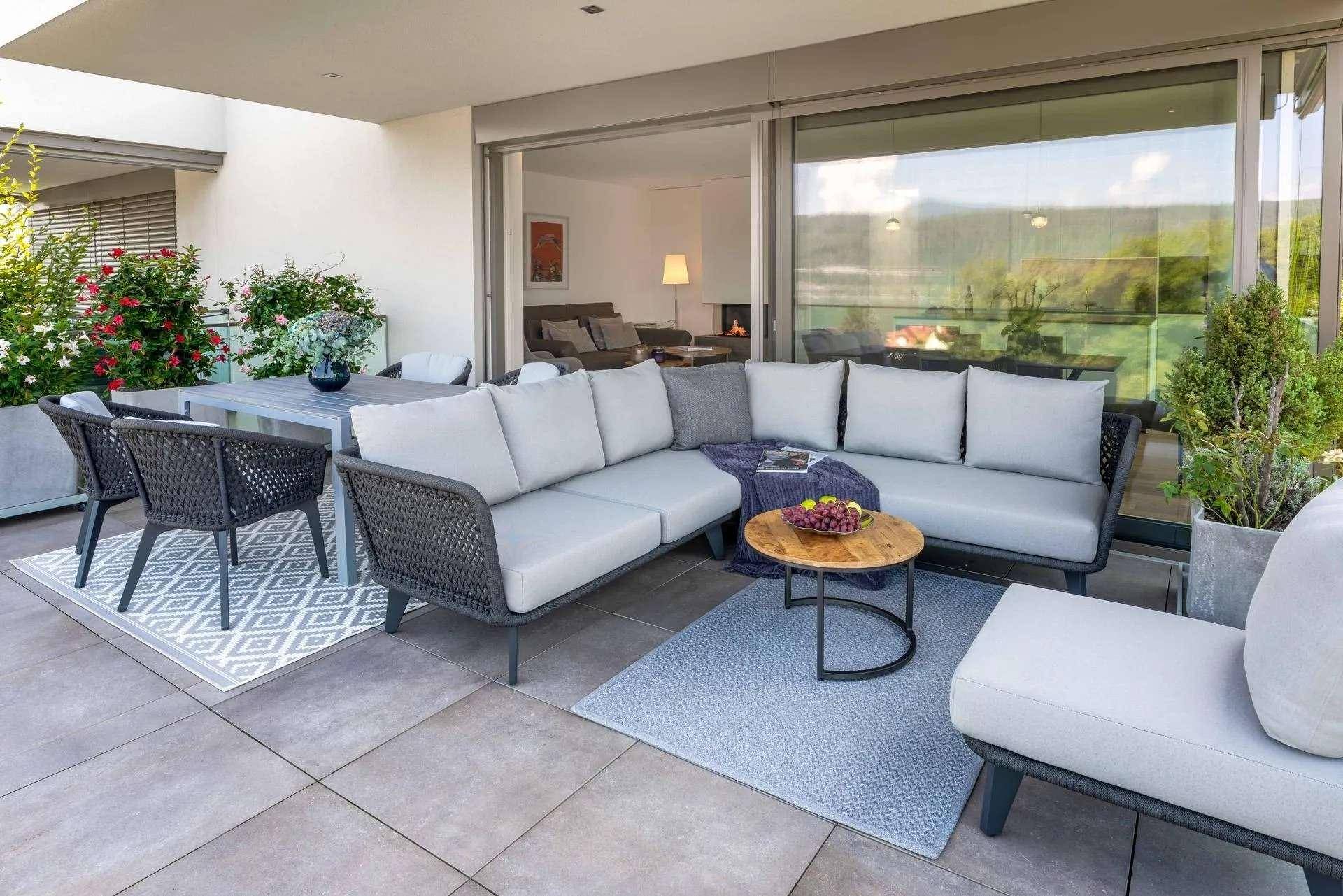Geräumige Terrasse mit bequemen Lounge-Möbeln und Essbereich, verbunden mit dem Innenraum durch Schiebetüren.