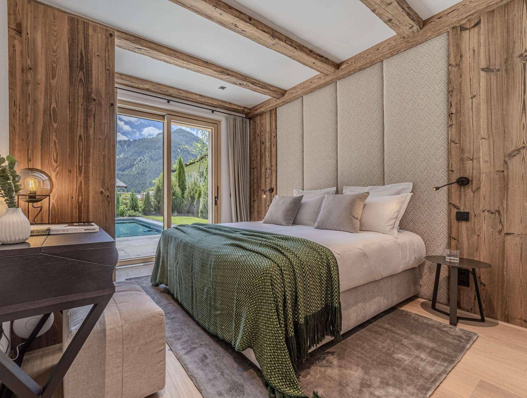Helles Schlafzimmer mit Holzbalken, gepolstertem Kopfteil und Poolzugang.