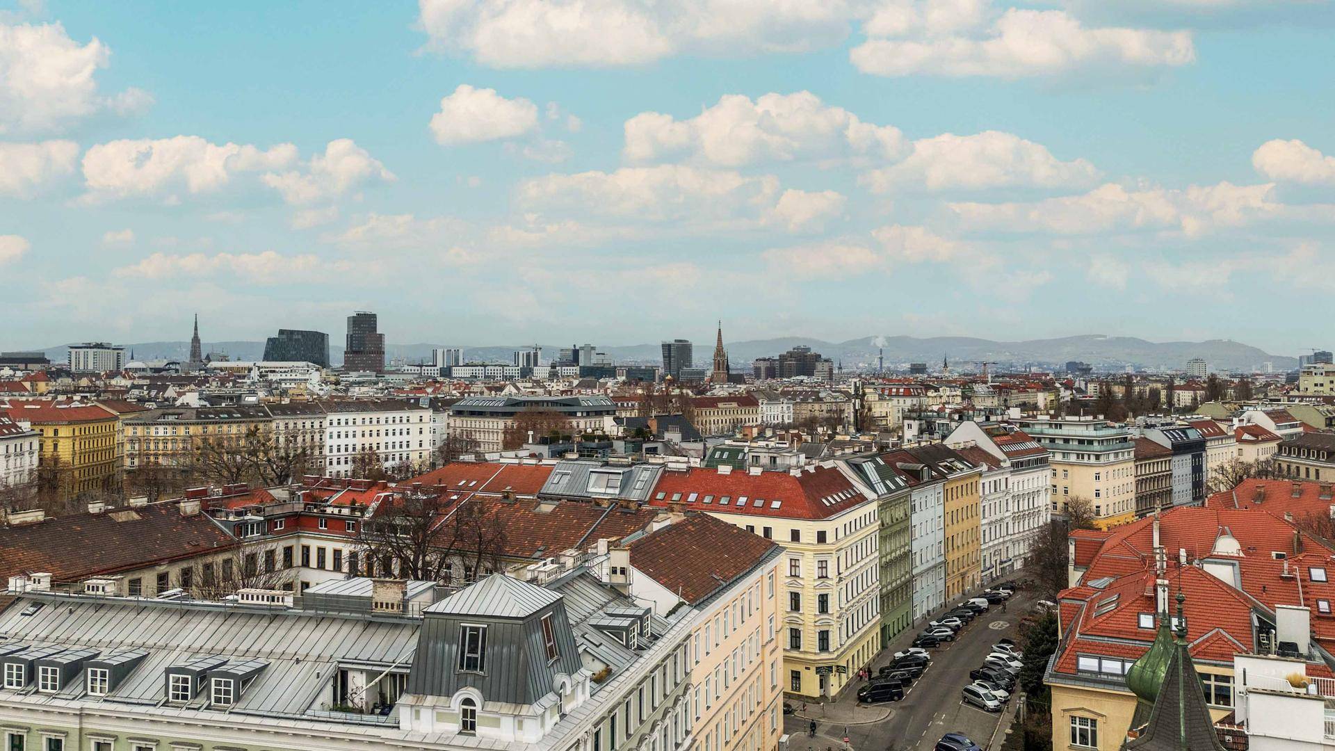 Weitläufiger Panoramablick über die Stadt mit zahlreichen Gebäuden und Bergen am Horizont.