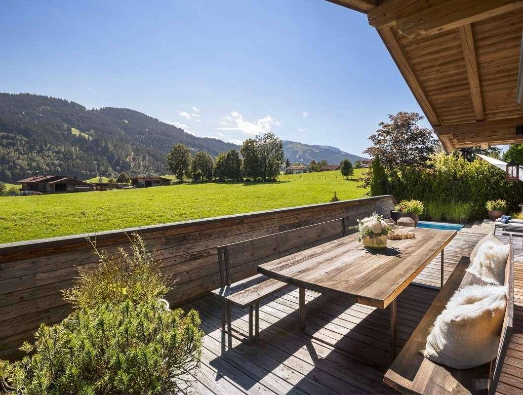 Gemütlicher Essbereich im Freien auf einer Holzterrasse mit weitem Blick auf die Alpenwiesen.
