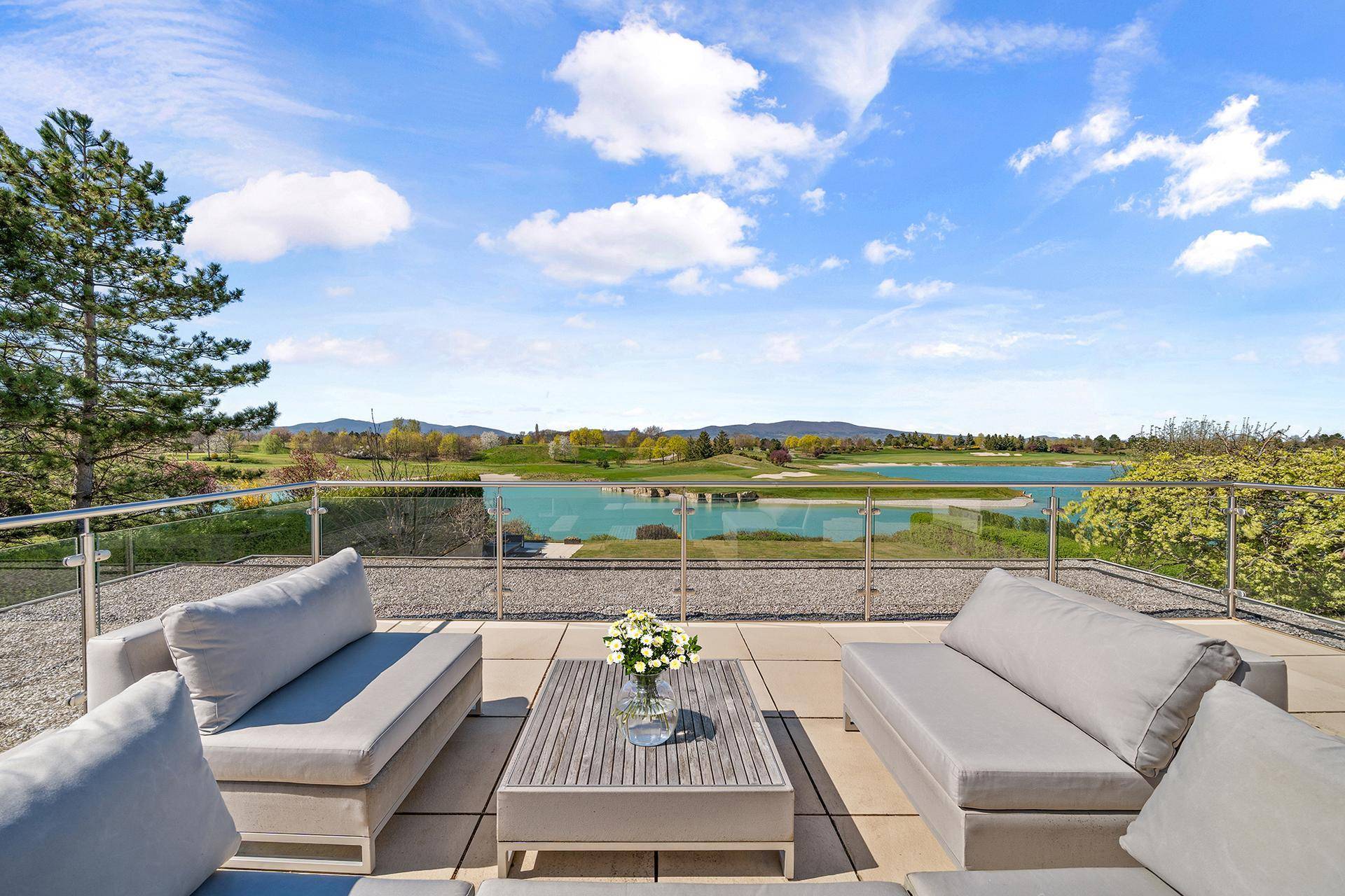Exklusive Dachterrasse mit Lounge-Möbeln und atemberaubendem Panoramablick auf See und Golfplatz.