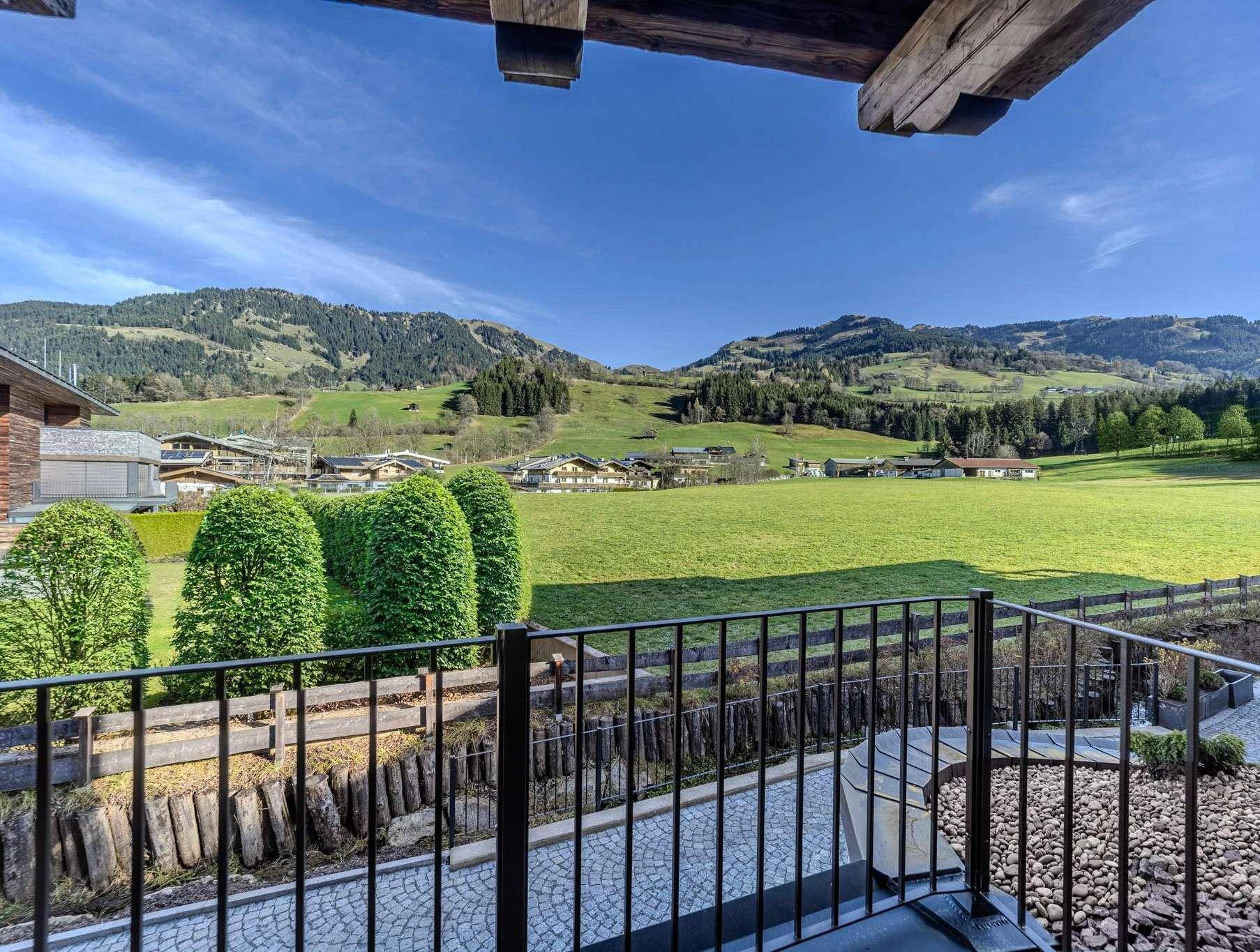 Balkon mit schmiedeeisernem Geländer und weitem Blick auf die grüne Berglandschaft.