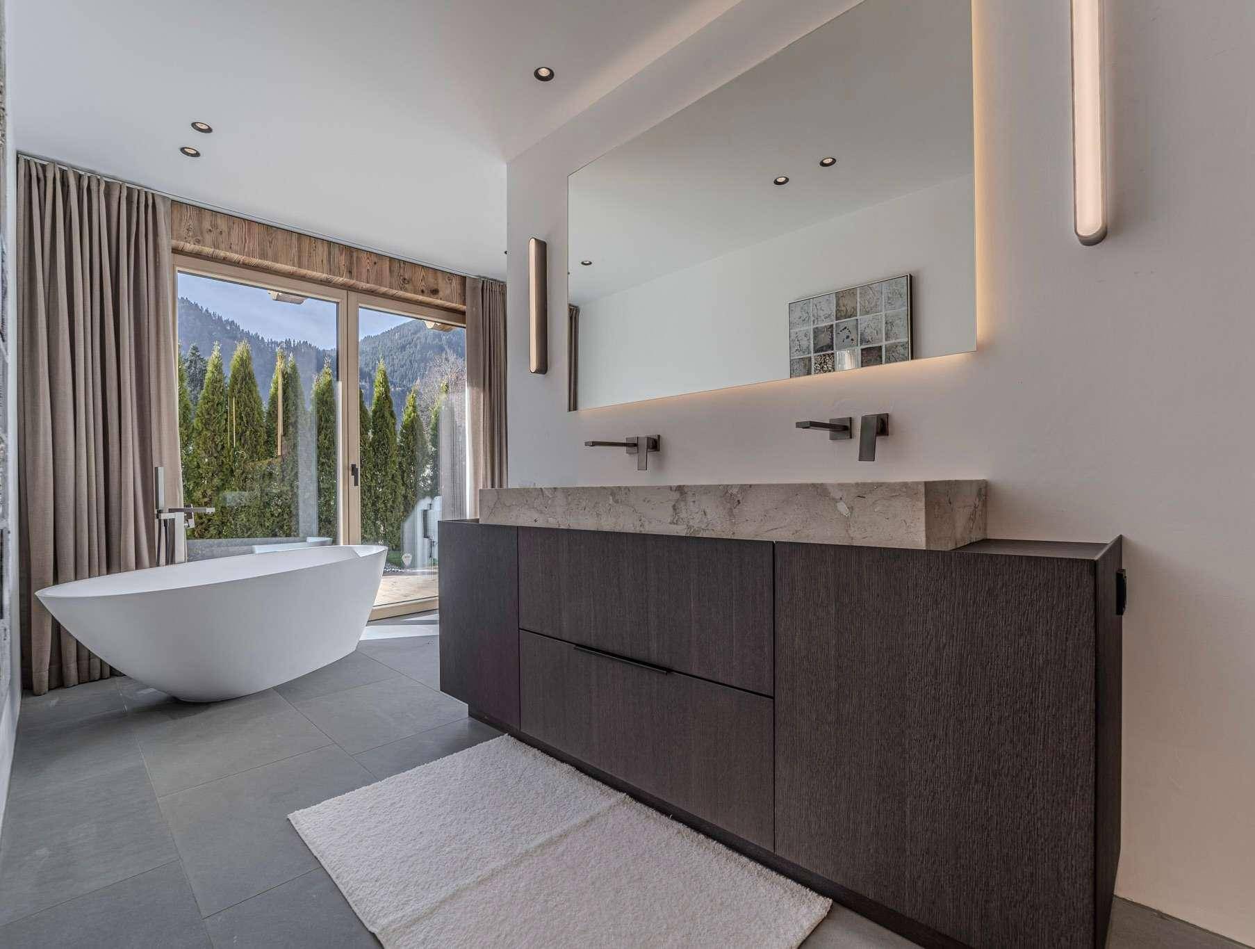 Luxuriöses Badezimmer mit freistehender Badewanne, Doppelwaschbecken und Bergblick.