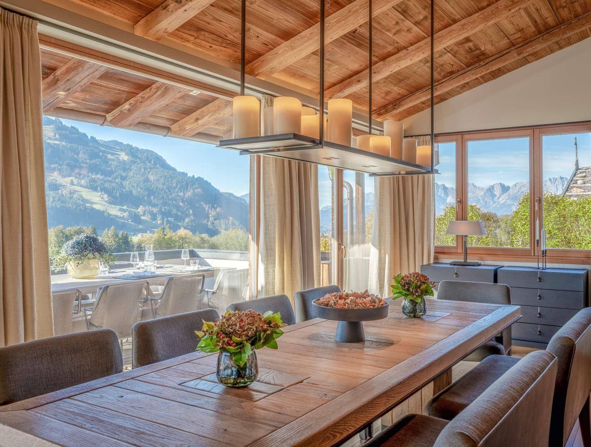 Gemütlicher Essbereich mit Holztisch, Holzbalkendecke und weitem Blick auf die Berge.