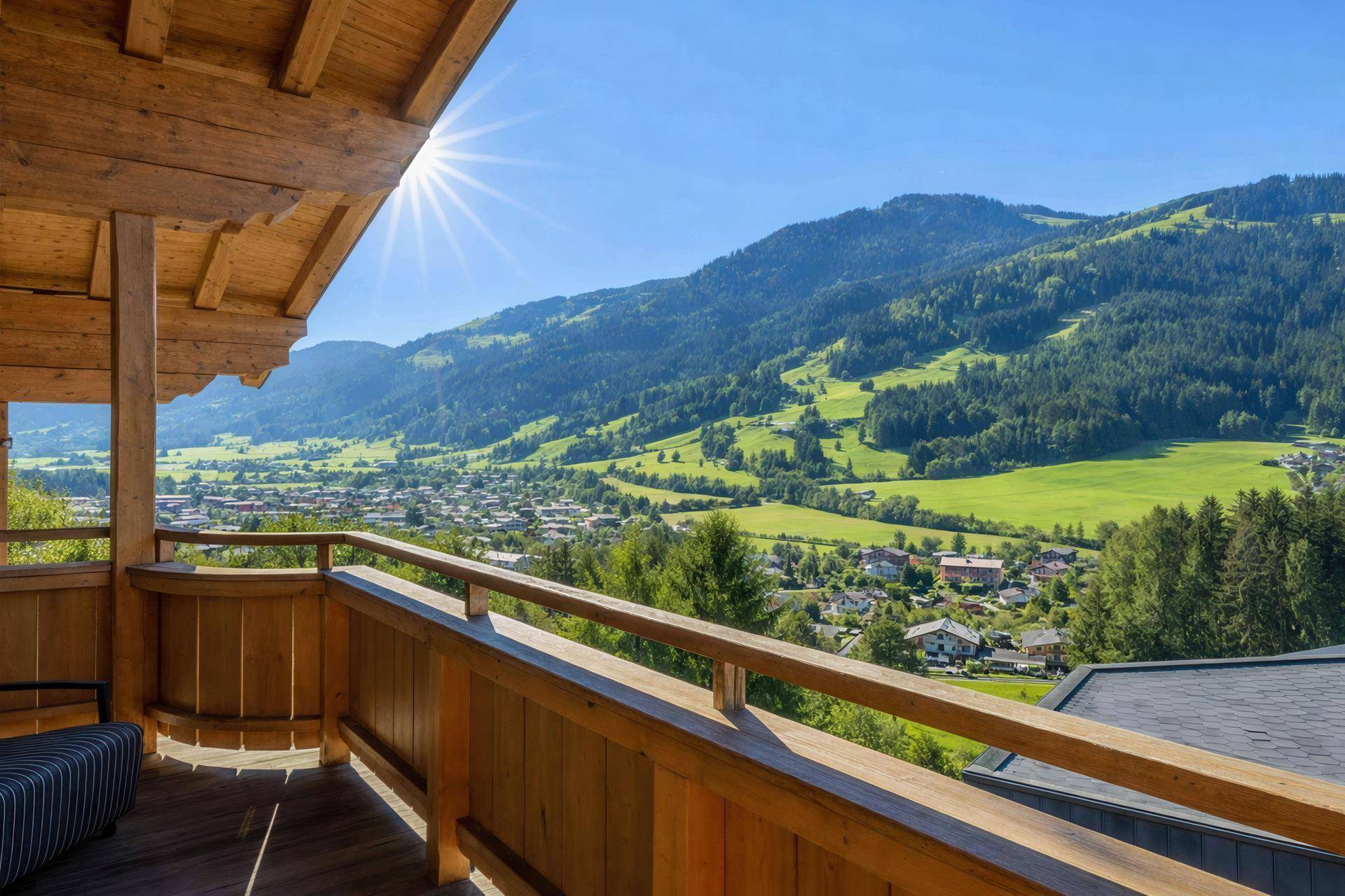 Sonniger Holzbalkon mit weitem Blick über das Tal und die umliegende Berglandschaft.