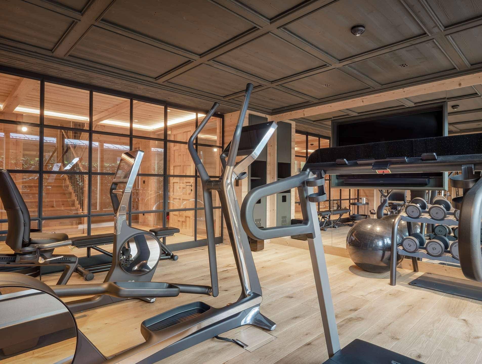 Gut ausgestatteter Fitnessraum mit modernen Trainingsgeräten und Holzboden in luxuriöser Umgebung.