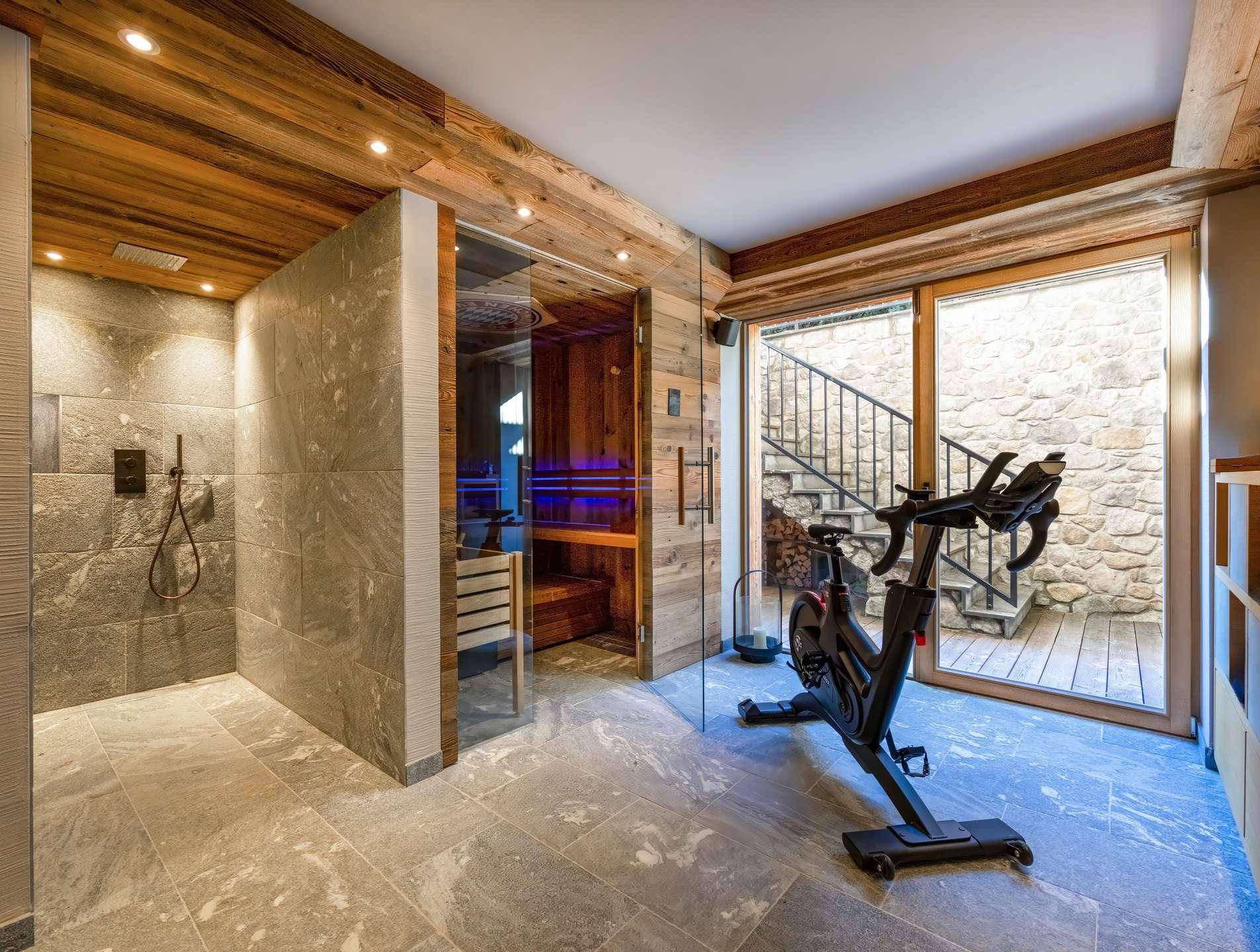 Wellnessbereich mit Sauna, Dusche und Fitnessgerät, mit Zugang zu einem privaten Patio.