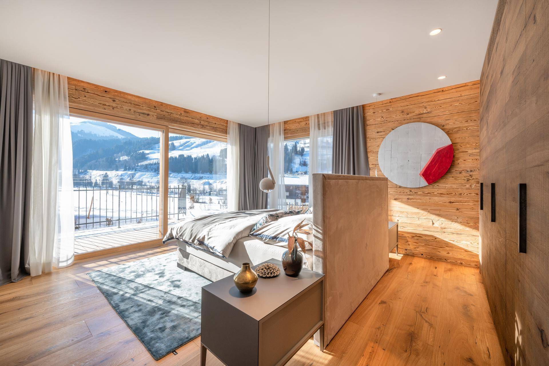 Helles Schlafzimmer mit Holzwänden, großem Bett und direktem Zugang zum Balkon mit Bergblick.