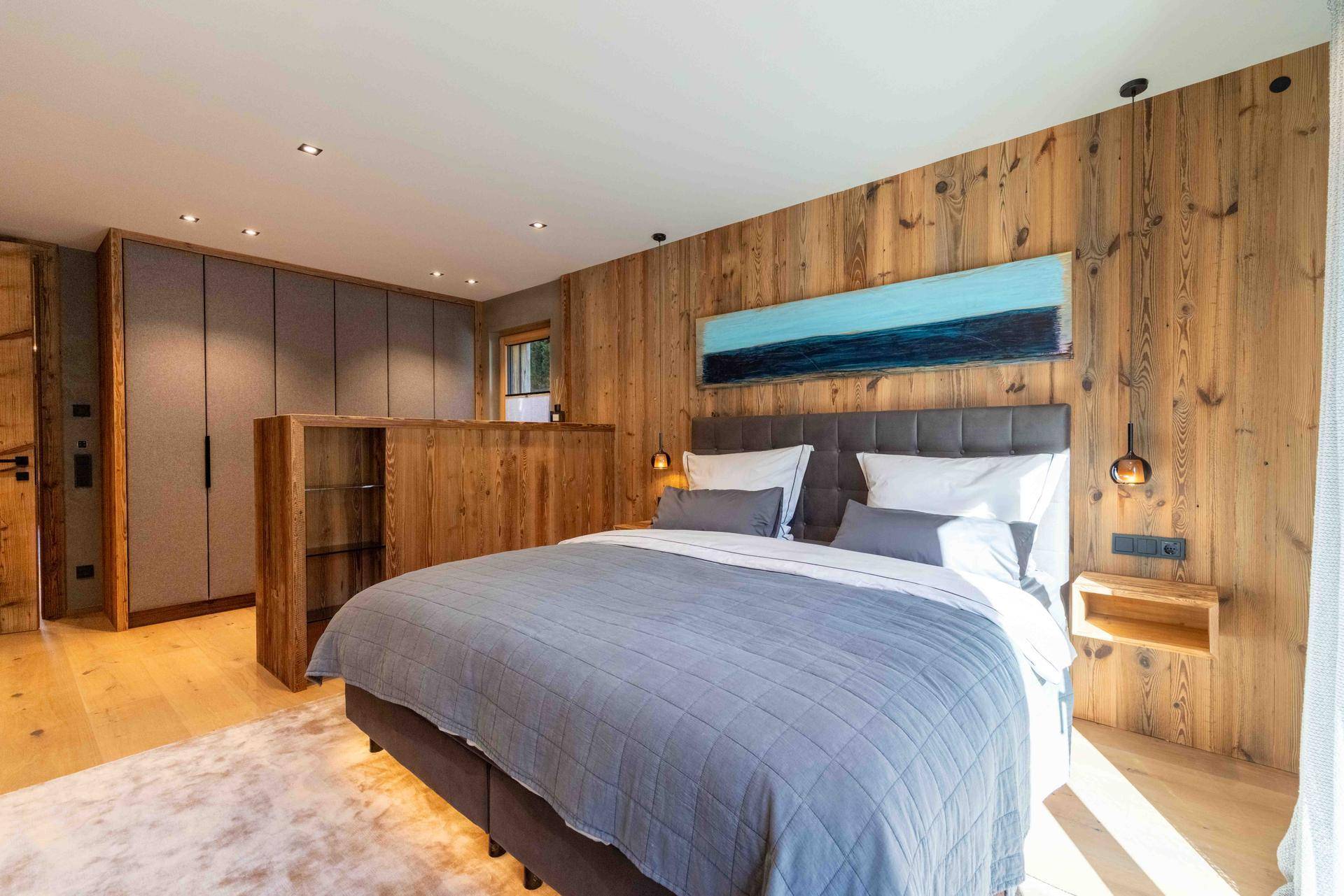 Gemütliches Schlafzimmer mit Holzwänden, Einbauschränken und modernem Bett.