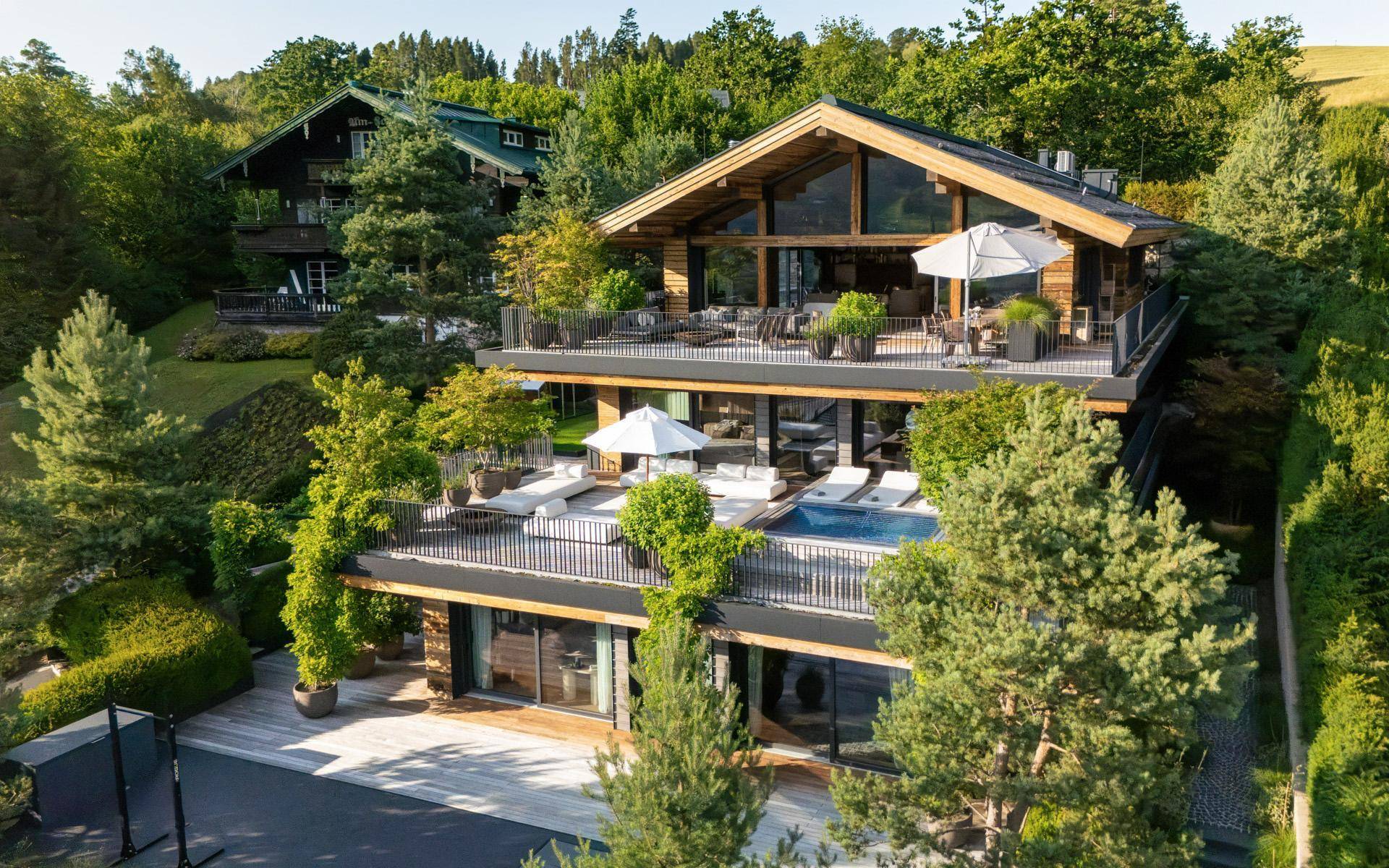 Luxuriöses Chalet mit mehreren Terrassen, einem Pool und weitläufiger Grünanlage in alpiner Umgebung.