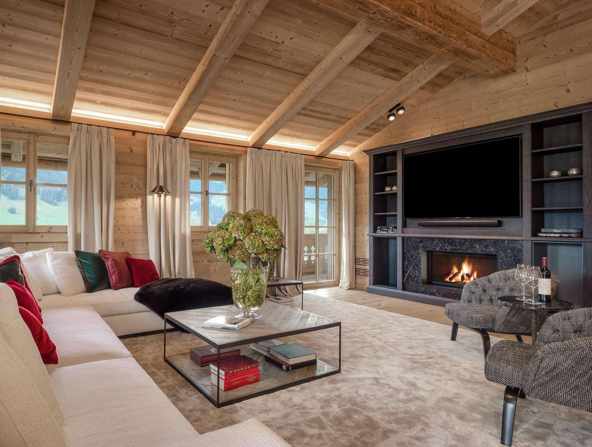 Gemütliches Wohnzimmer mit integriertem Kamin, Holzwänden und Blick auf die umliegende Natur.