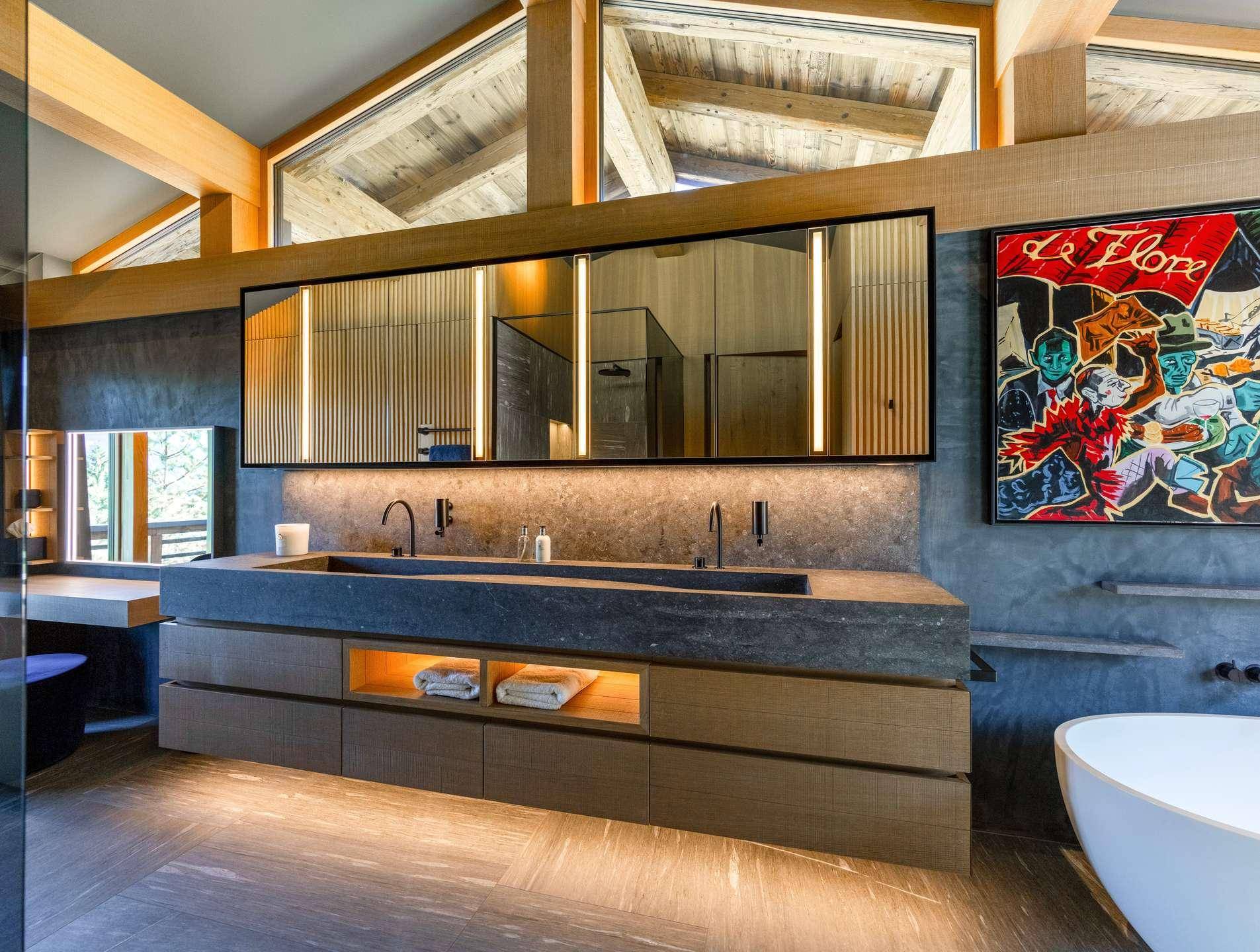 Luxuriöses Badezimmer mit Doppelwaschbecken, Steinplatte und moderner Beleuchtung.