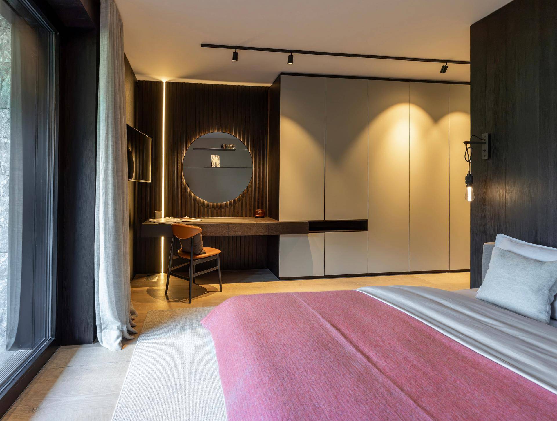 Modernes Schlafzimmer mit integrierten Schränken, Schreibtisch und indirekter Beleuchtung.