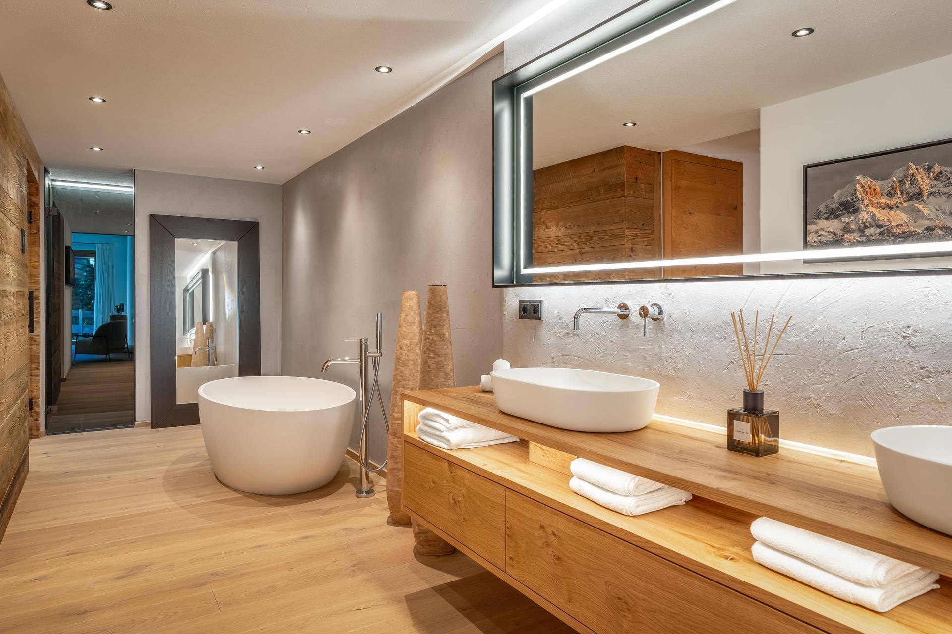 Luxuriöses Badezimmer mit freistehender Badewanne, Doppelwaschbecken und Holzwaschtisch.