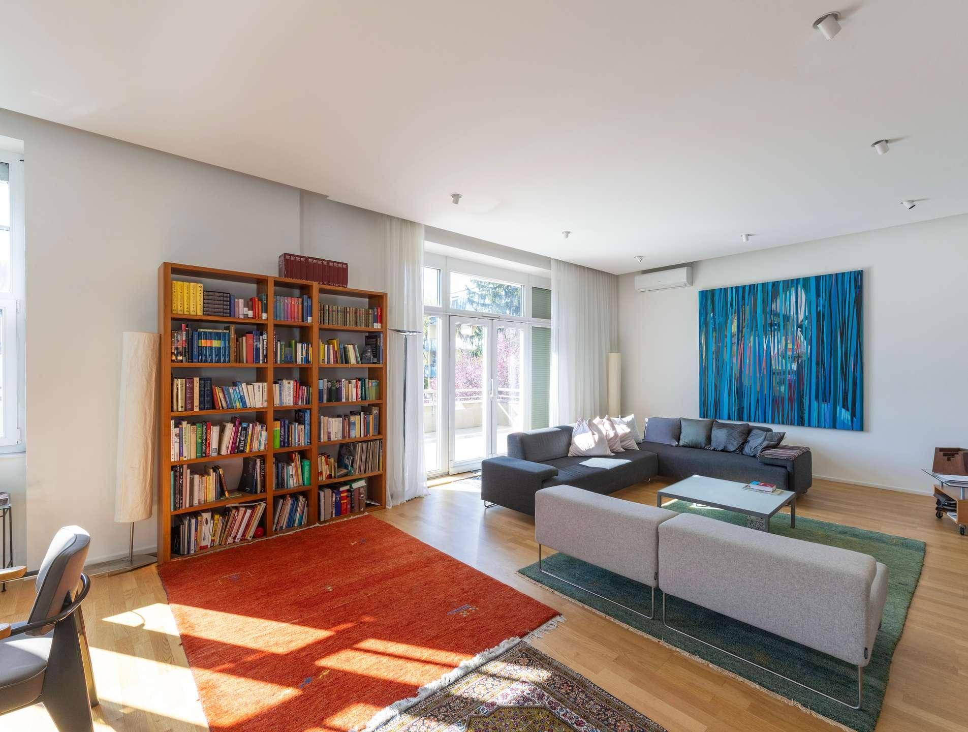 Modernes Wohnzimmer mit großem Sofa, Bücherregal und Zugang zur Terrasse.