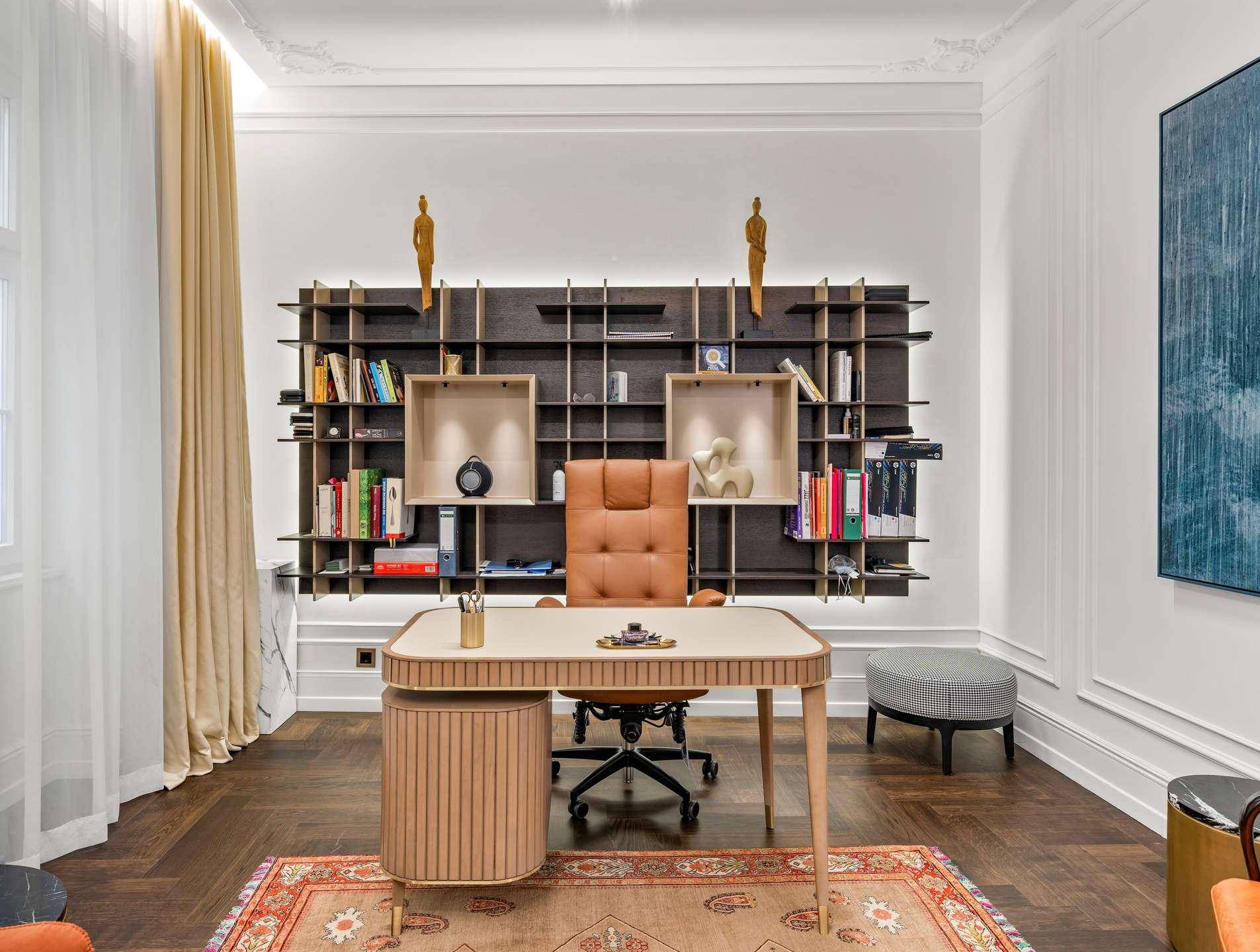 Elegantes Arbeitszimmer mit großem Schreibtisch, maßgefertigtem Bücherregal und Fischgrätparkett.