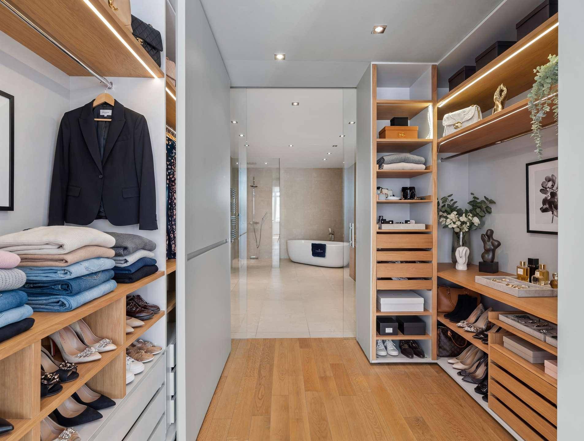 Begehbarer Kleiderschrank mit integrierten Regalen und Zugang zu einem luxuriösen Badezimmer.