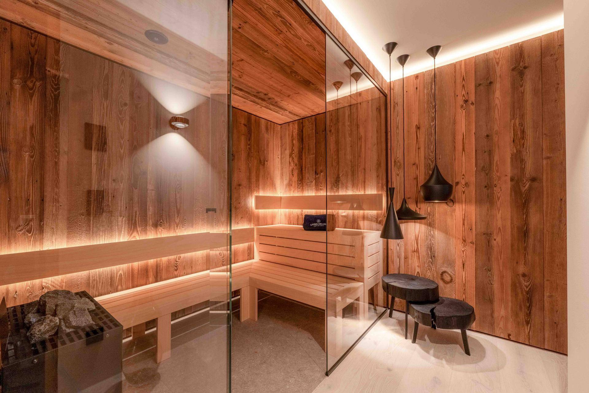 Moderne Sauna mit Holzbänken, Glasfront und indirekter Beleuchtung für Entspannung.