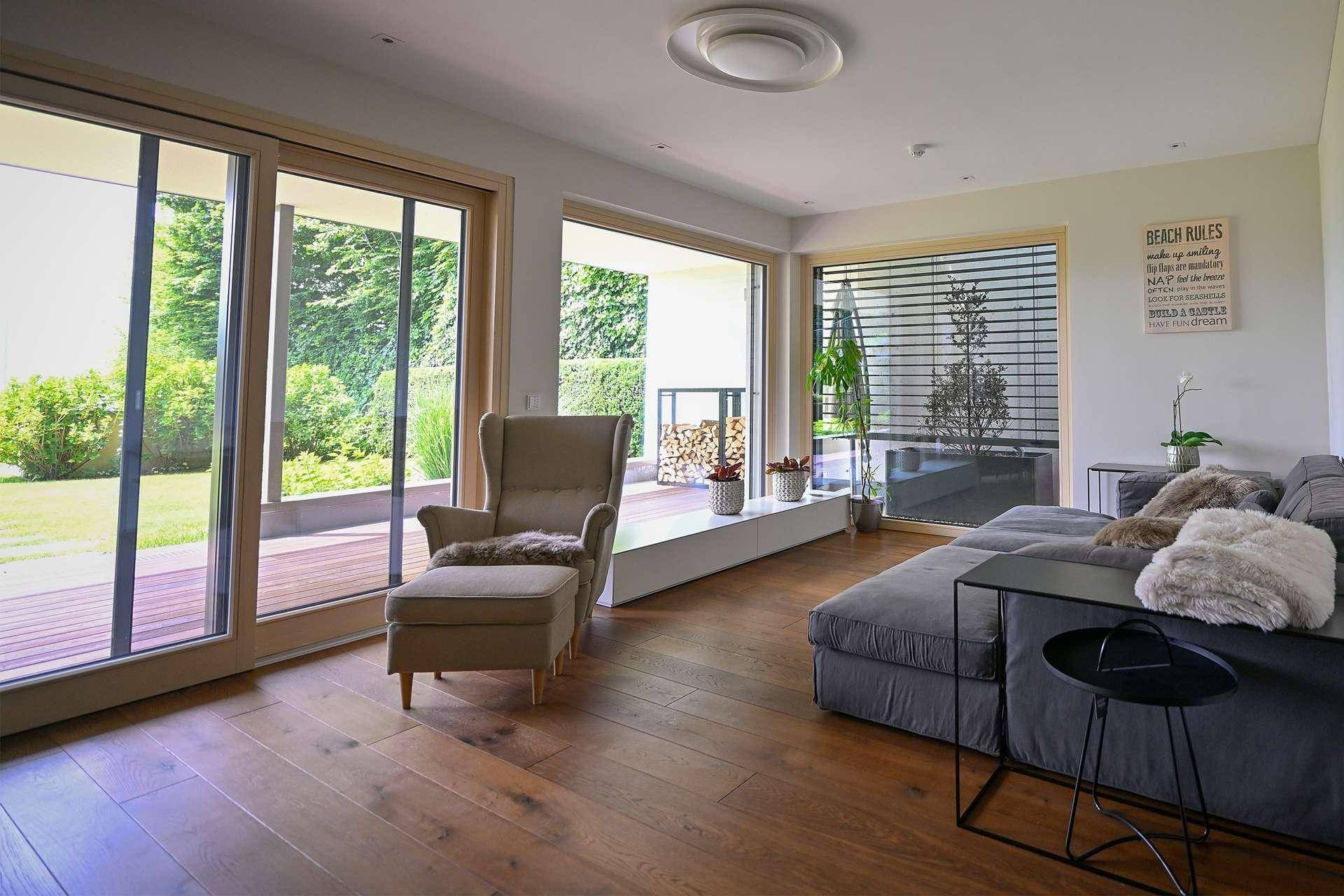 Geräumiges Wohnzimmer mit Holzboden, bequemen Sitzmöbeln und großen Schiebetüren zum Garten.