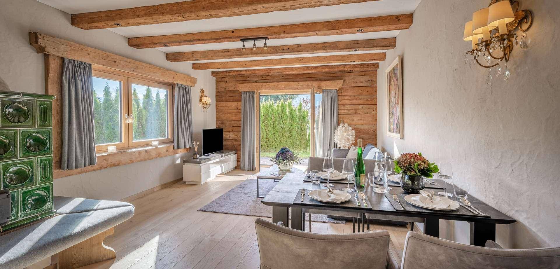 Gemütlicher Wohn-Essbereich mit Holzwänden, großem Esstisch und Zugang zur Terrasse.