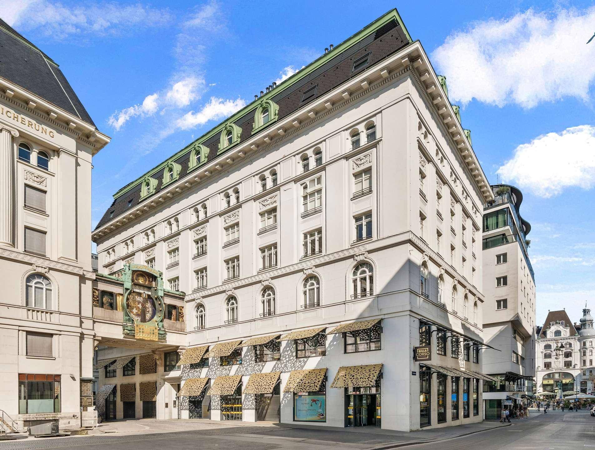 Elegantes historisches Gebäude mit grünen Dächern und Geschäften im Erdgeschoss.