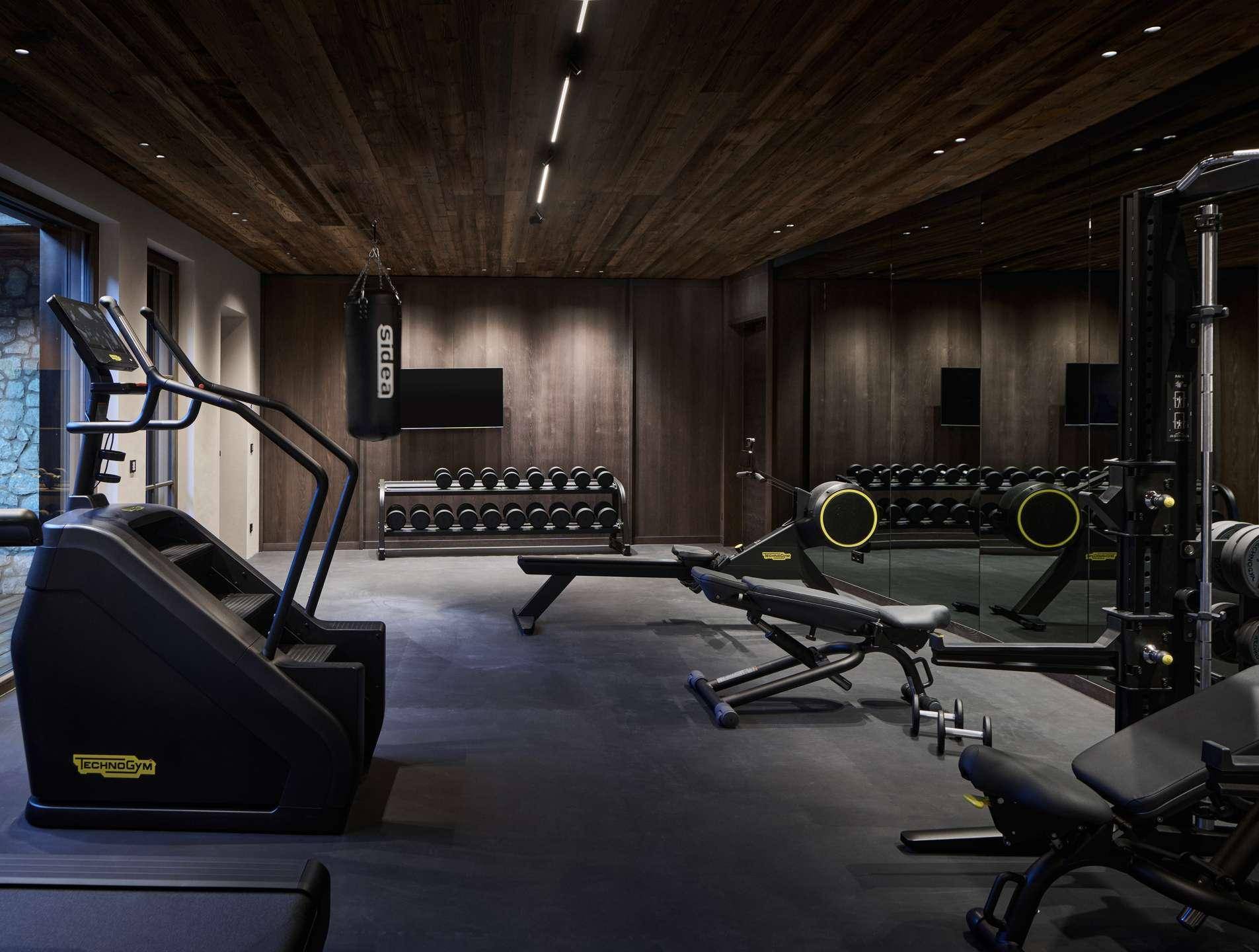 Gut ausgestatteter Fitnessraum mit verschiedenen Trainingsgeräten und Spiegelflächen.