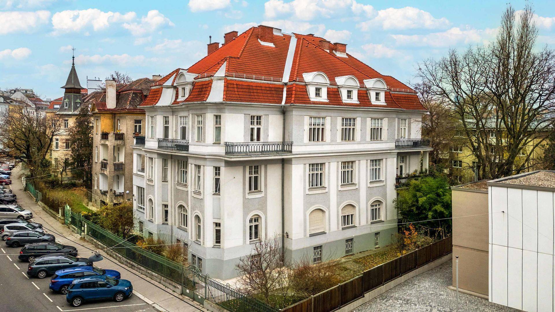 Elegante Fassade eines historischen Gebäudes mit weißen Wänden, vielen Fenstern und kleinen Balkonen.