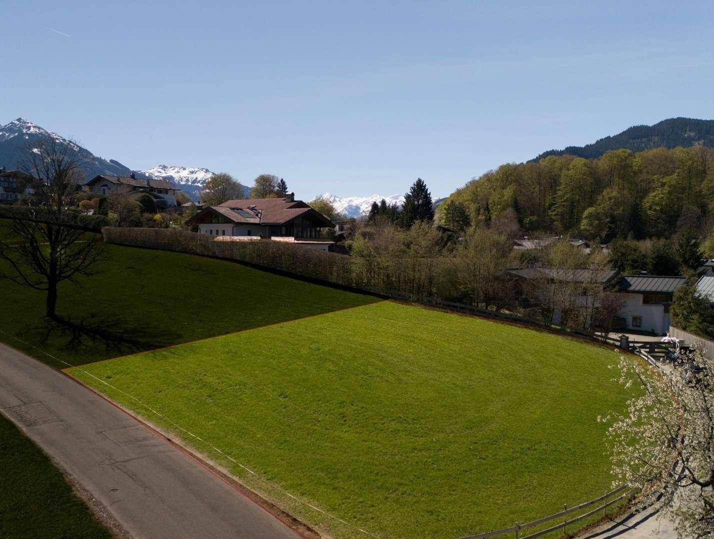 Grünes Baugrundstück in sonniger Hanglage mit Blick auf die umliegende Bergwelt.