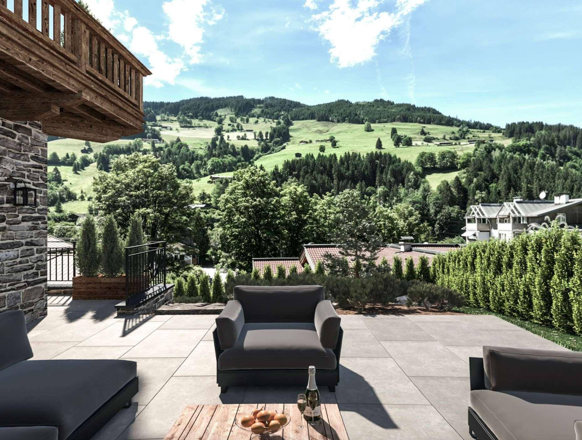 Geräumige Terrasse mit modernen Lounge-Möbeln und weitem Blick auf die grüne Hügellandschaft.