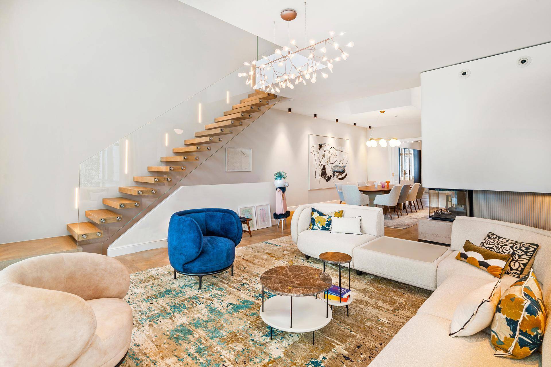 Helles Wohnzimmer mit stilvollen Möbeln, Parkettboden und offener Treppe zum Obergeschoss.
