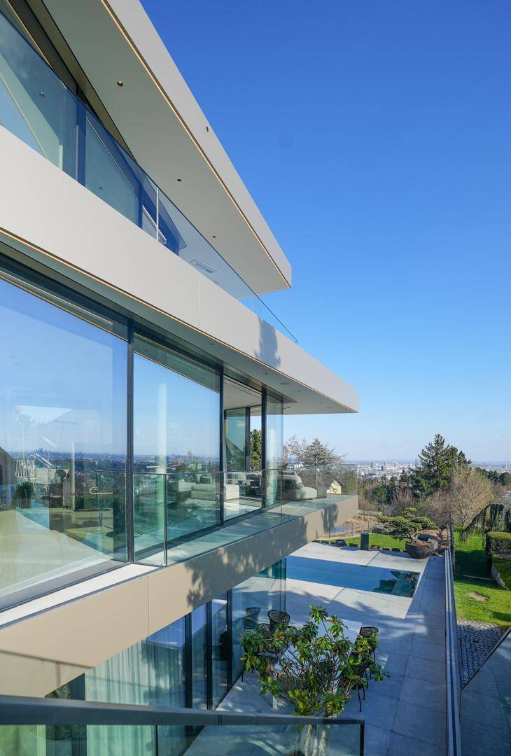 Elegante Terrassenbereiche einer modernen Villa mit weitem Blick über die Stadt und viel Grün.