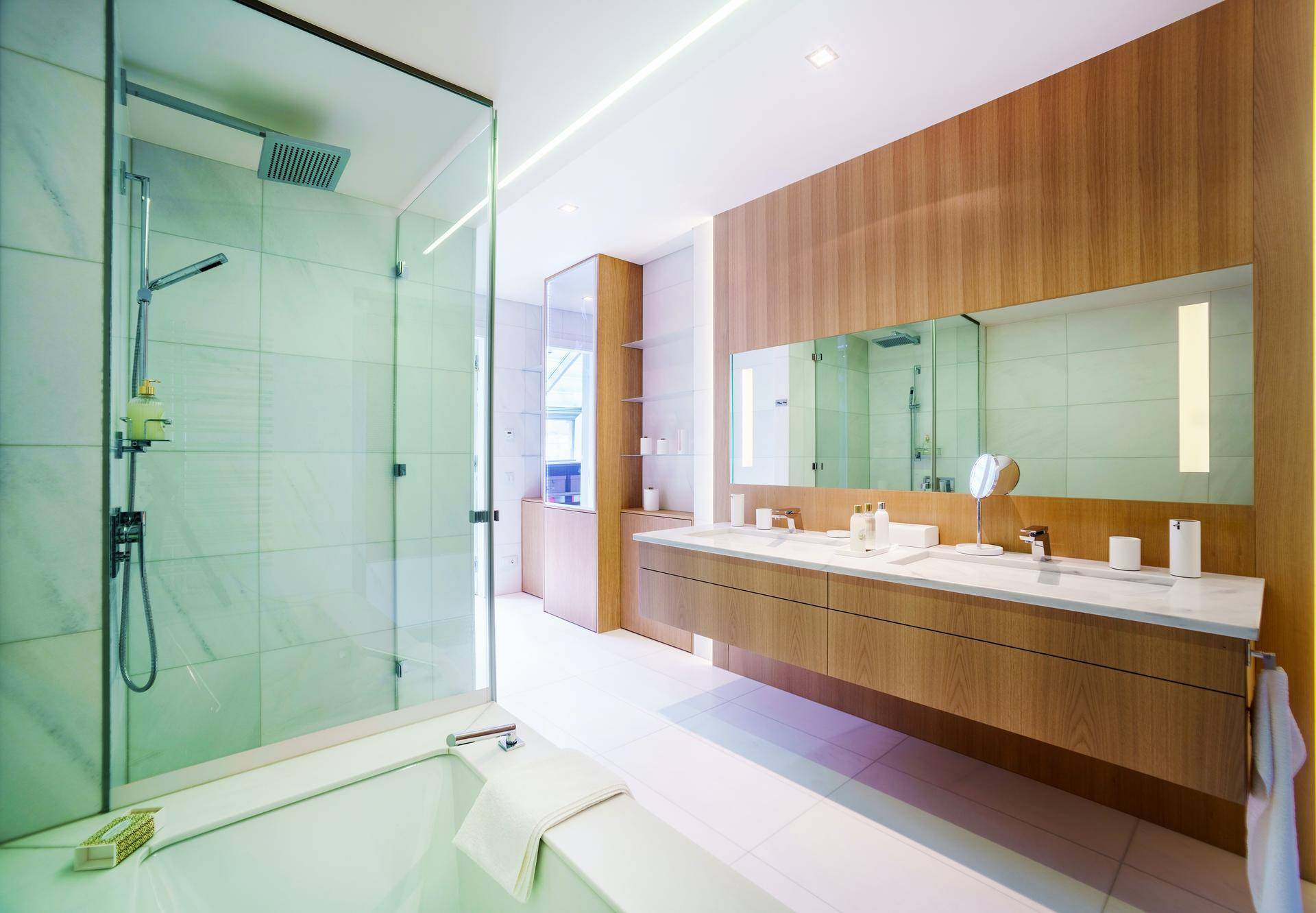 Luxuriöses Badezimmer mit begehbarer Dusche, Badewanne, Doppelwaschbecken und eleganten Holzdetails.
