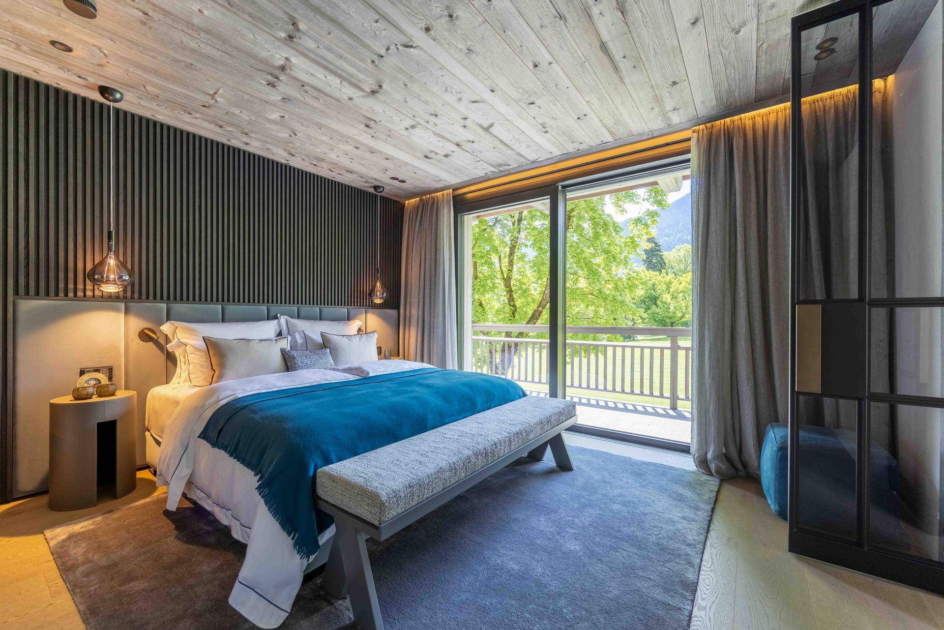 Modernes Schlafzimmer mit großem Bett, Teppichboden und Zugang zum Balkon.