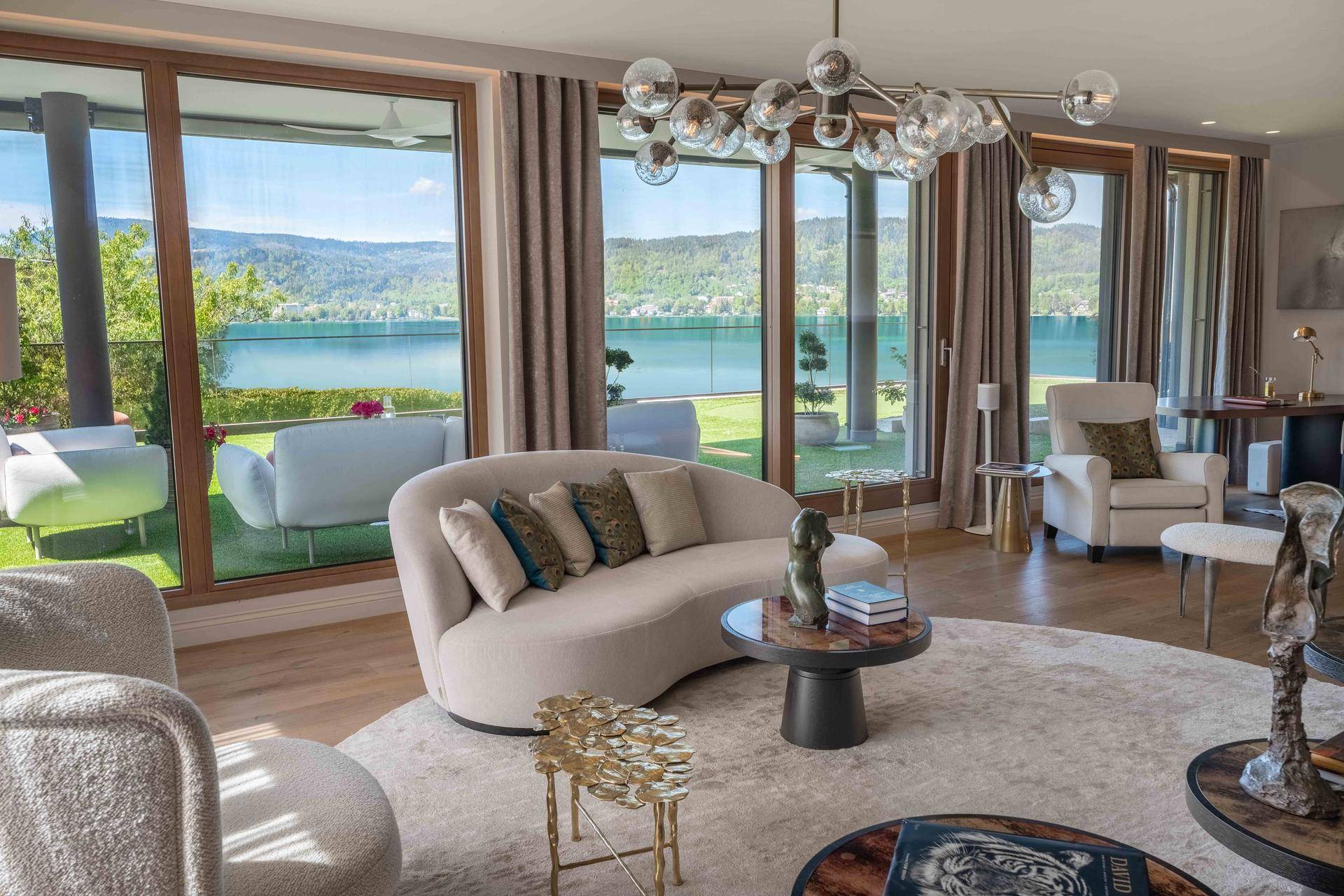 Großzügiges Wohnzimmer mit Seeblick, modernen Möbeln und direktem Zugang zur Außenterrasse.